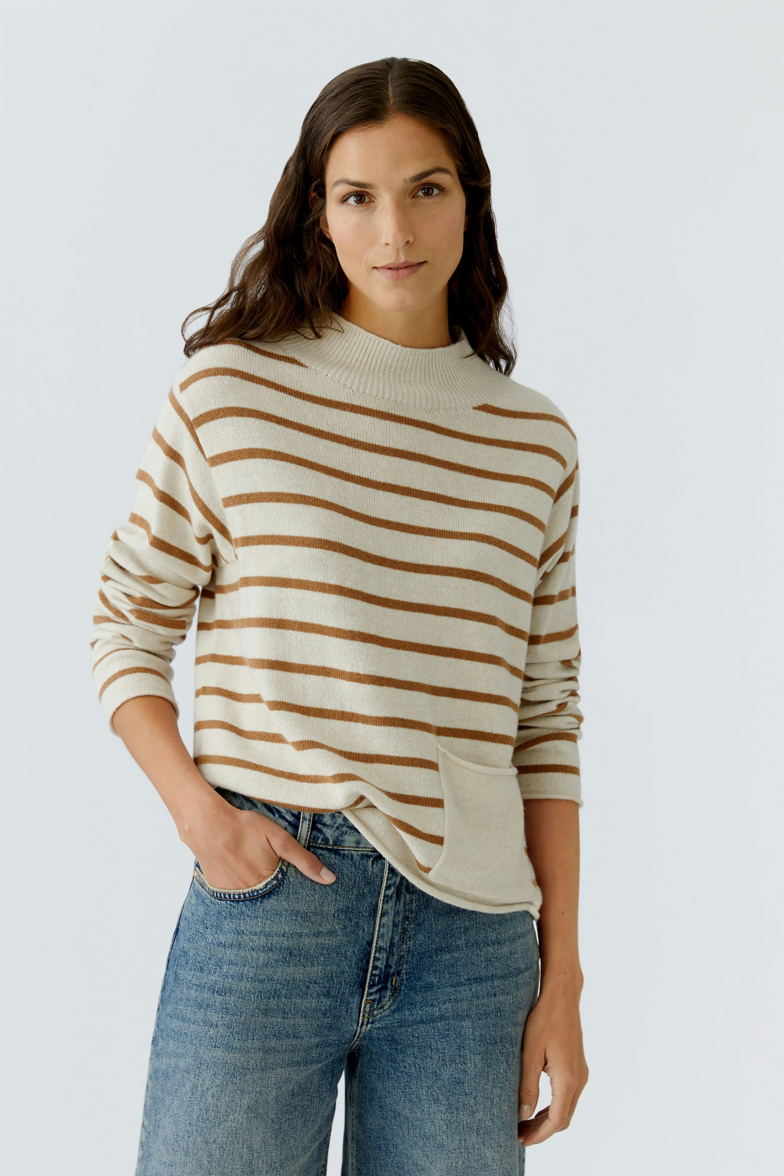 Bequemer Damen-Pullover: Frau in gestreiftem Pullover mit hohem Kragen und lässigen Jeans.