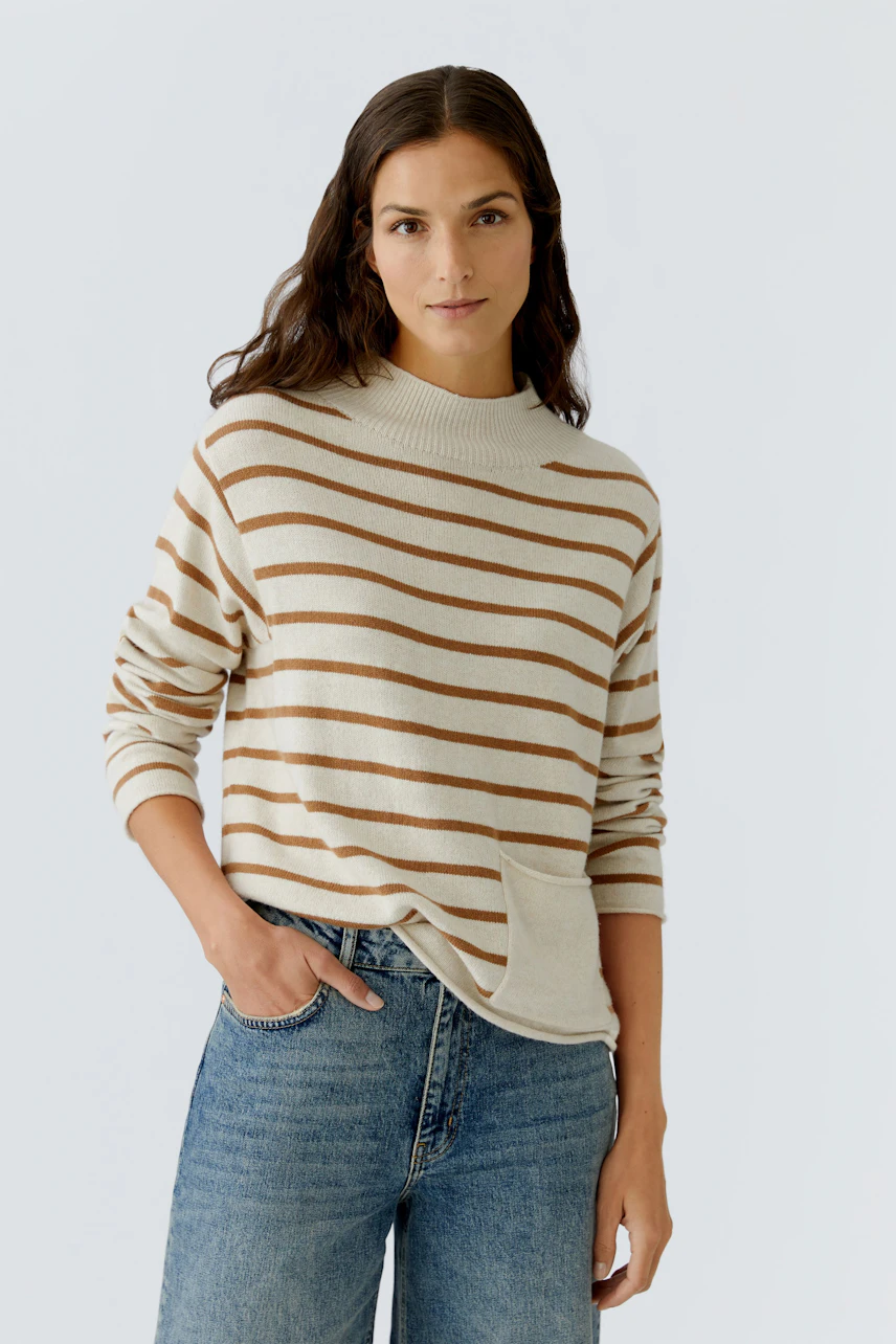 Bequemer Damen-Pullover: Frau in gestreiftem Pullover mit hohem Kragen und lässigen Jeans.