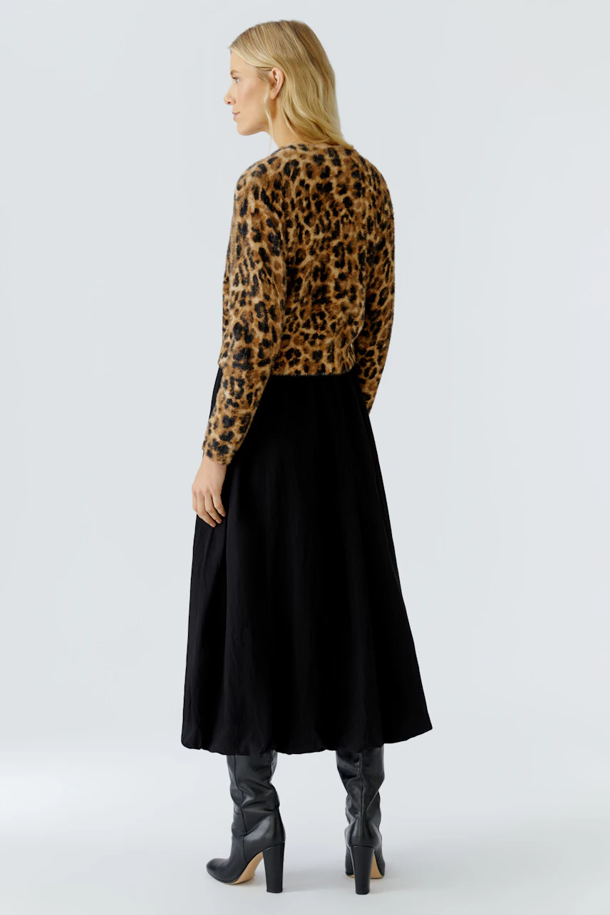 Damen-Pullover: Frau in einem braun-schwarzen Leo-Pullover mit langen Ärmeln und schwarzem Rock von hinten.