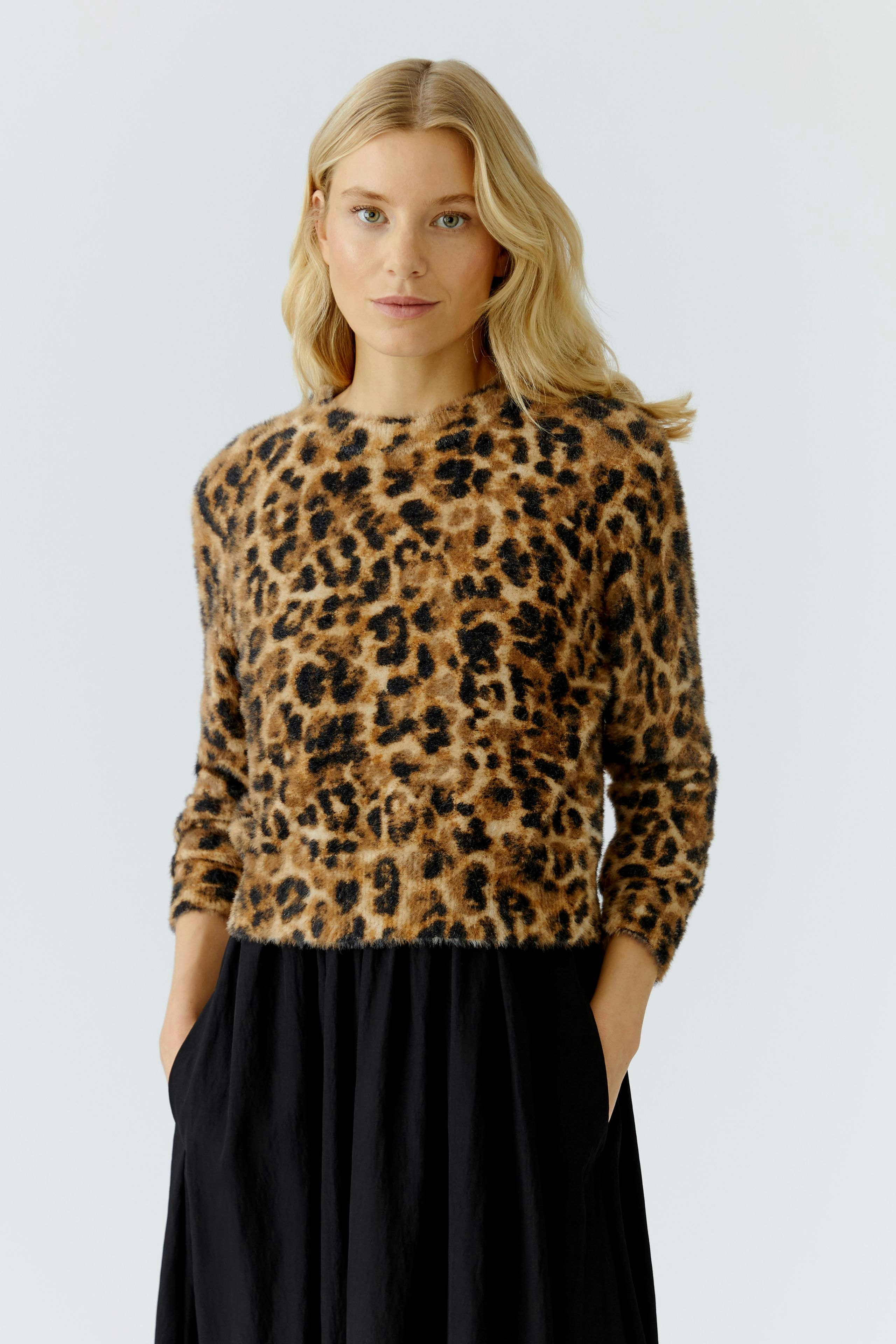 Casual women's pullover: A woman in a leopard print pullover with a relaxed fit, paired with a flowing skirt.