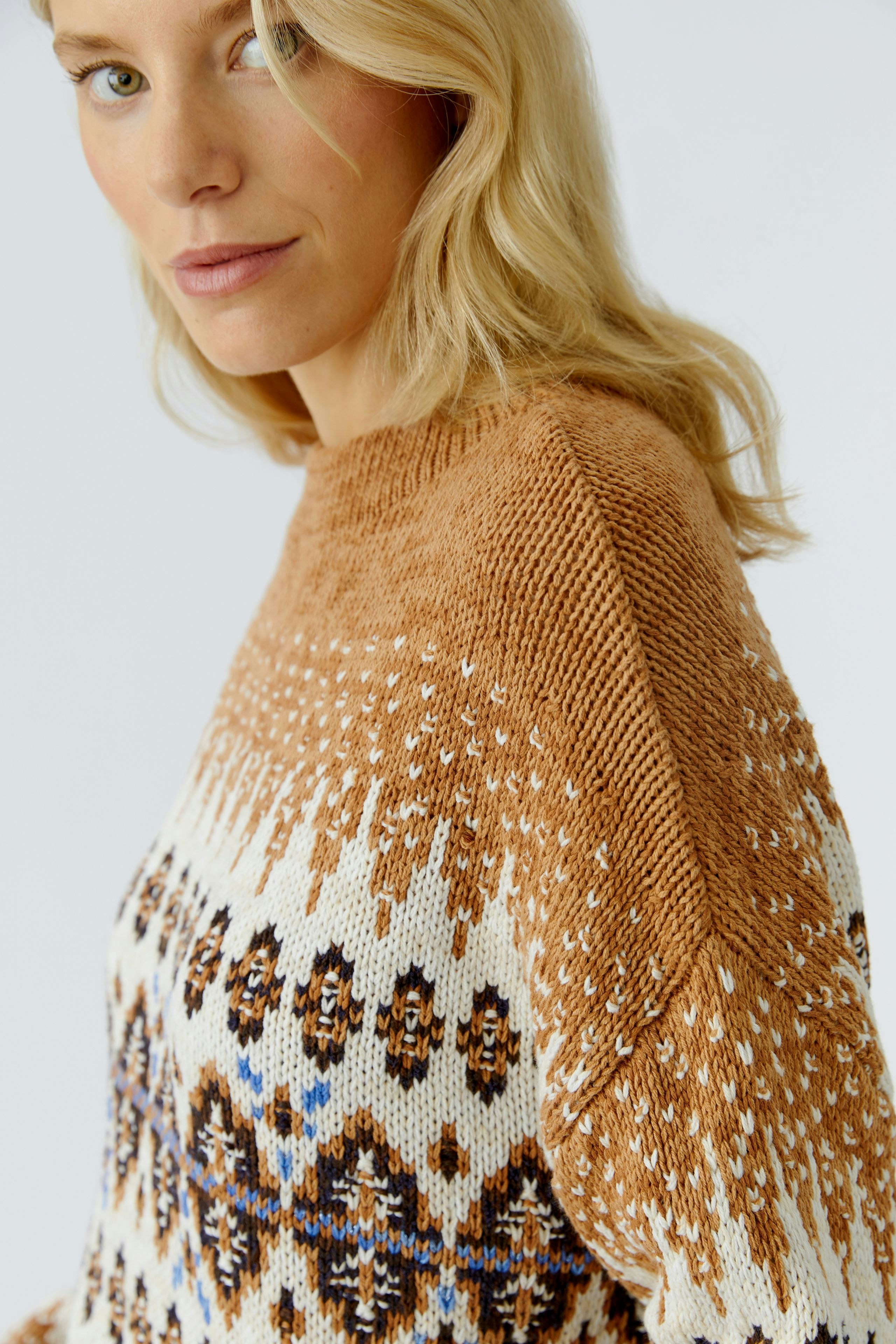 Modern women's pullover: A woman in a cozy, patterned pullover with warm tones and relaxed fit.