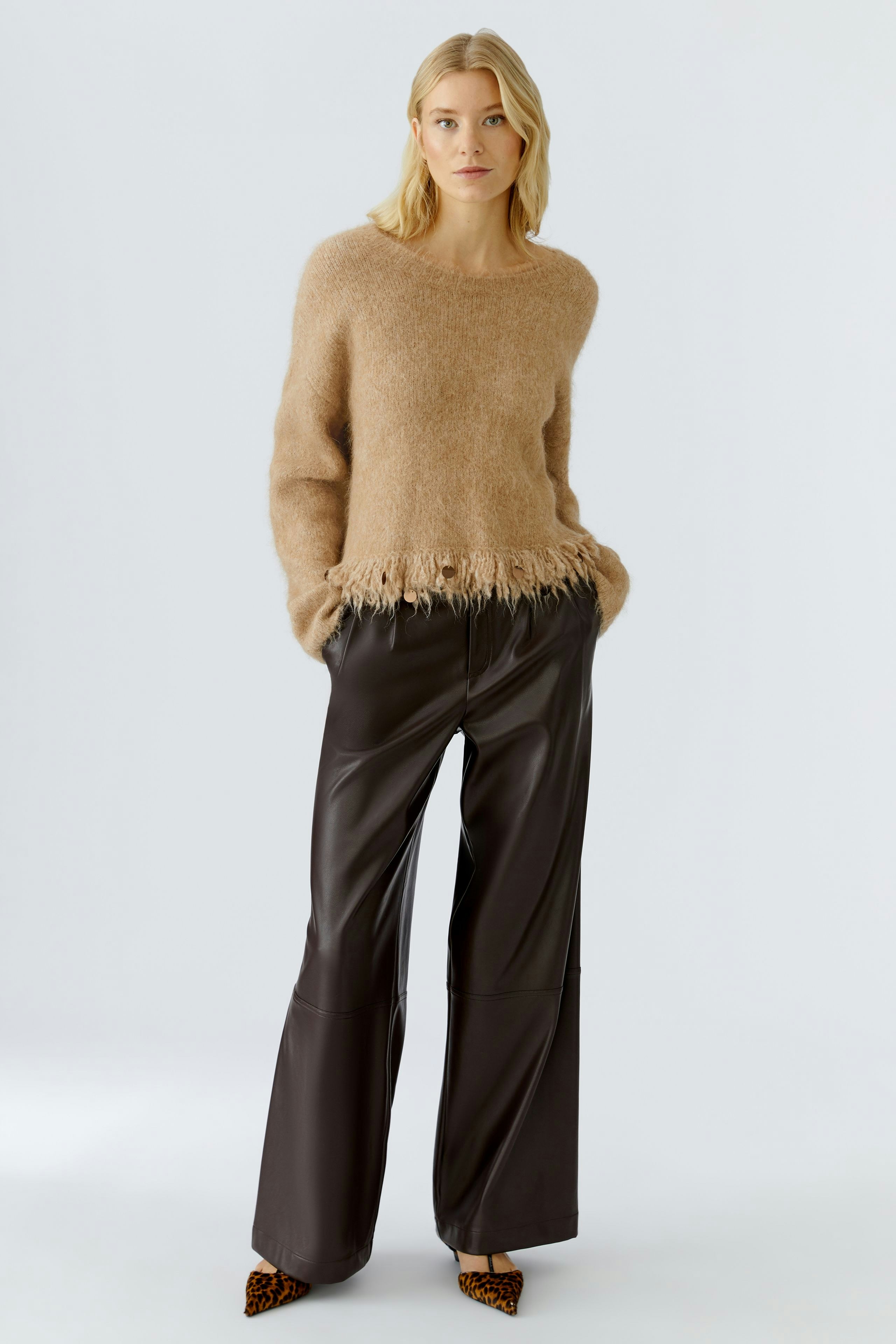 Casual women's pullover: A woman in a soft beige pullover with fringed hem and relaxed fit.