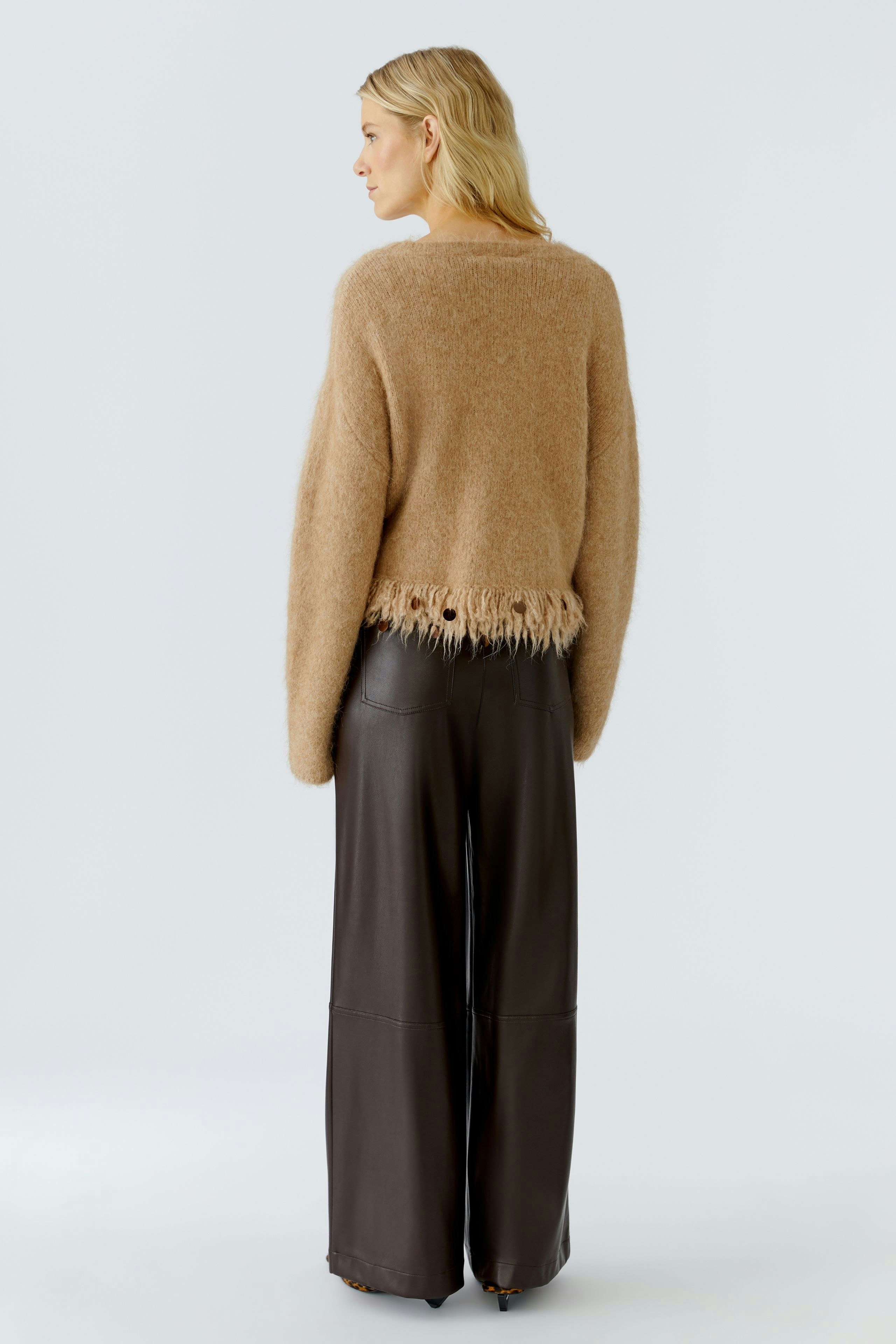 Casual women's pullover: A woman in a soft brown pullover with fringe detail, paired with wide-leg pants.