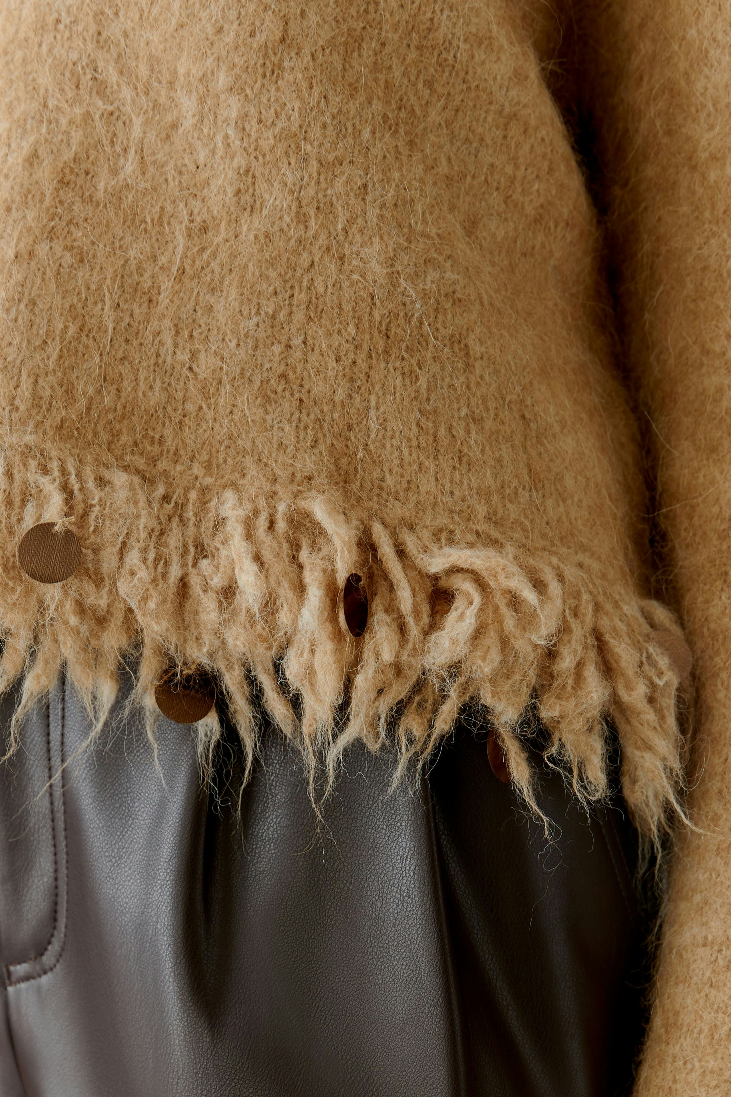 Cozy women's pullover in soft brown with a fringed hem and button details, perfect for casual wear.