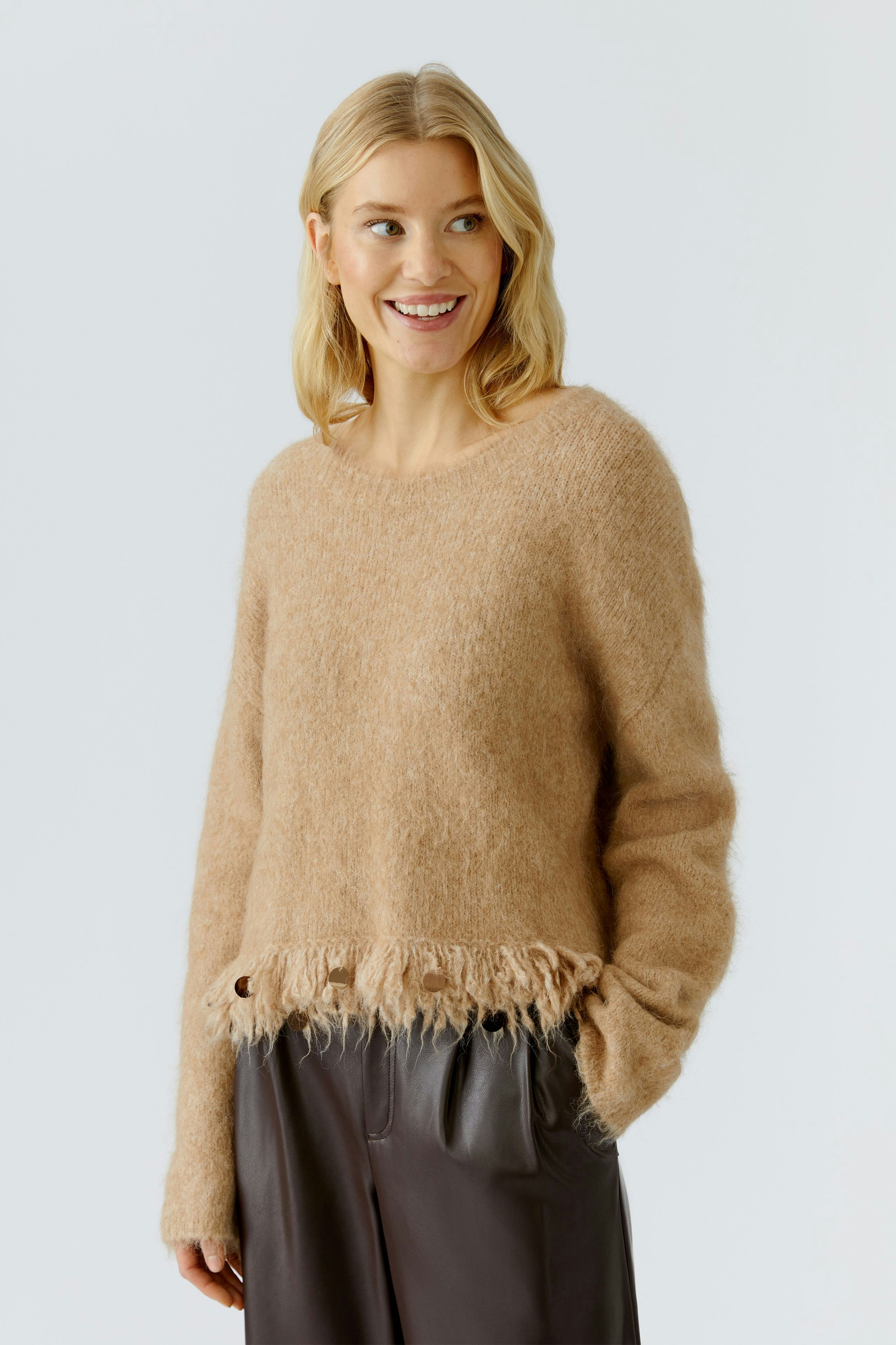Casual women's pullover: Smiling woman in a soft beige pullover with fringed hem and relaxed fit.