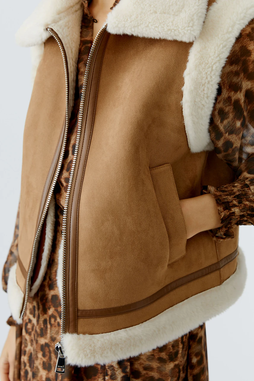 Stylish women's vest: A woman in a brown vest with a fluffy collar and side pockets.
