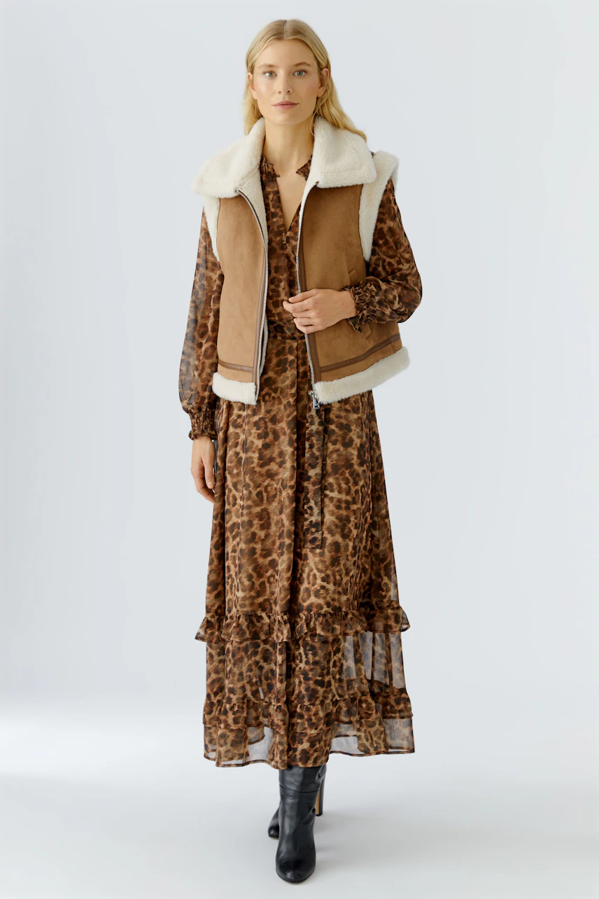 Casual women's vest: A woman in a brown vest with a soft collar over a leopard print dress.