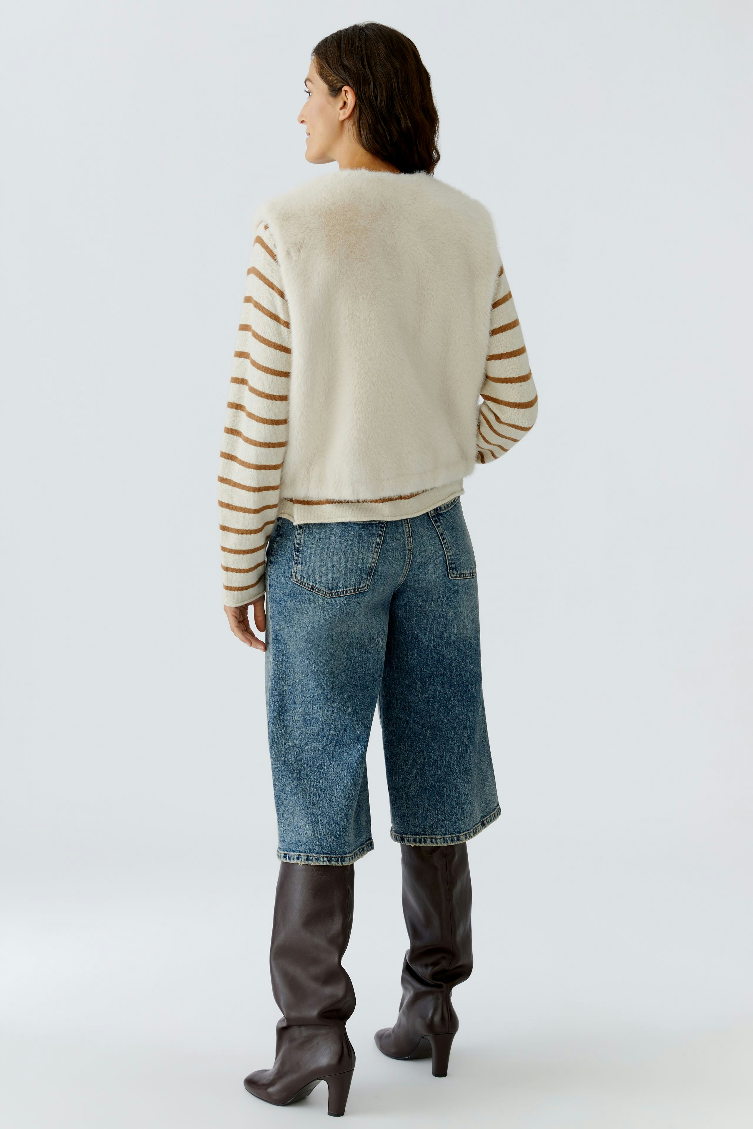 Casual women's vest: A woman in a striped vest with a soft texture, paired with relaxed denim shorts.