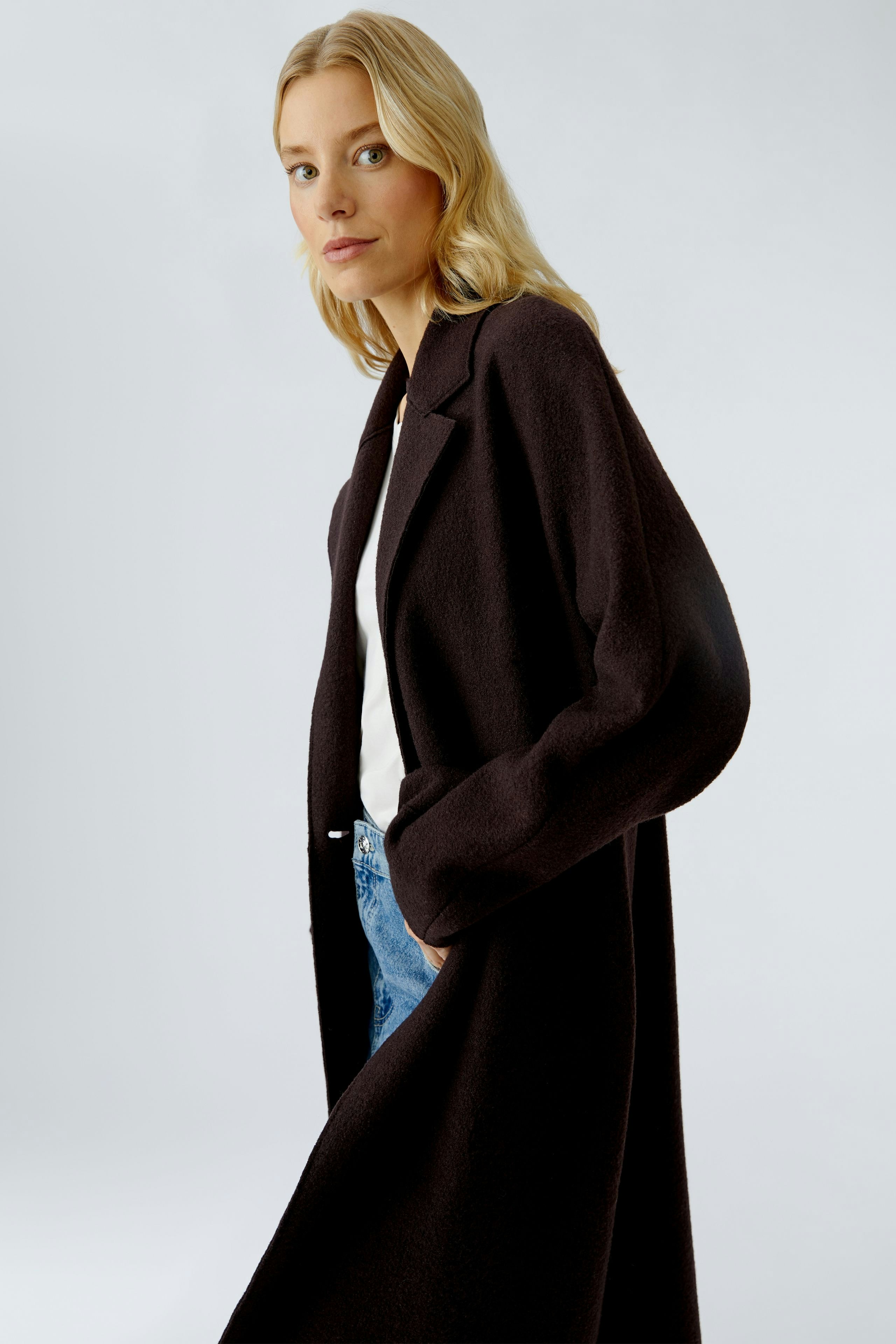 Modern women's winter coat: A woman in a dark coat with a relaxed fit and pockets.