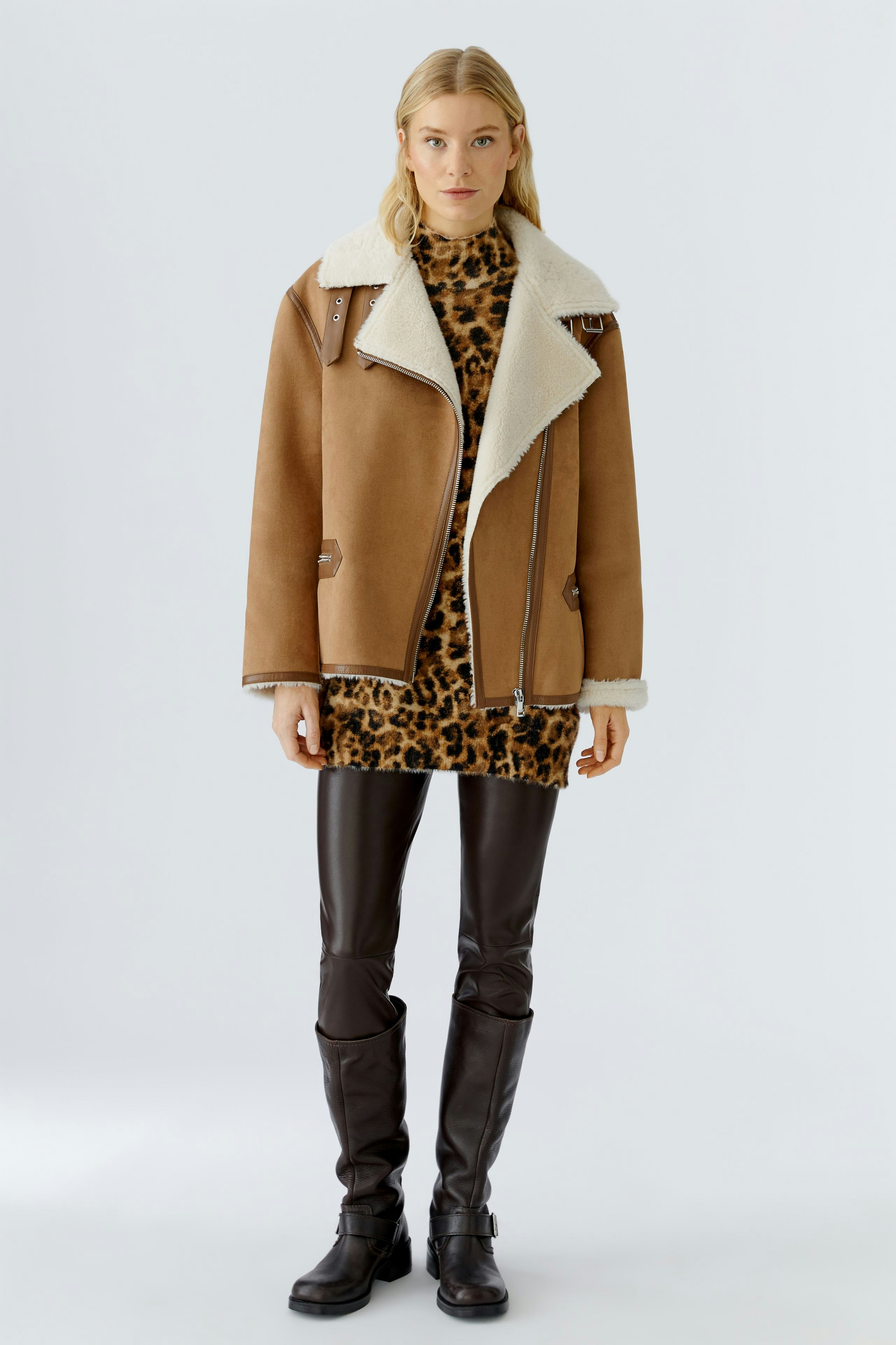 Casual outdoor jacket: Woman in a brown shearling jacket over a leopard print dress, exuding a relaxed vibe.