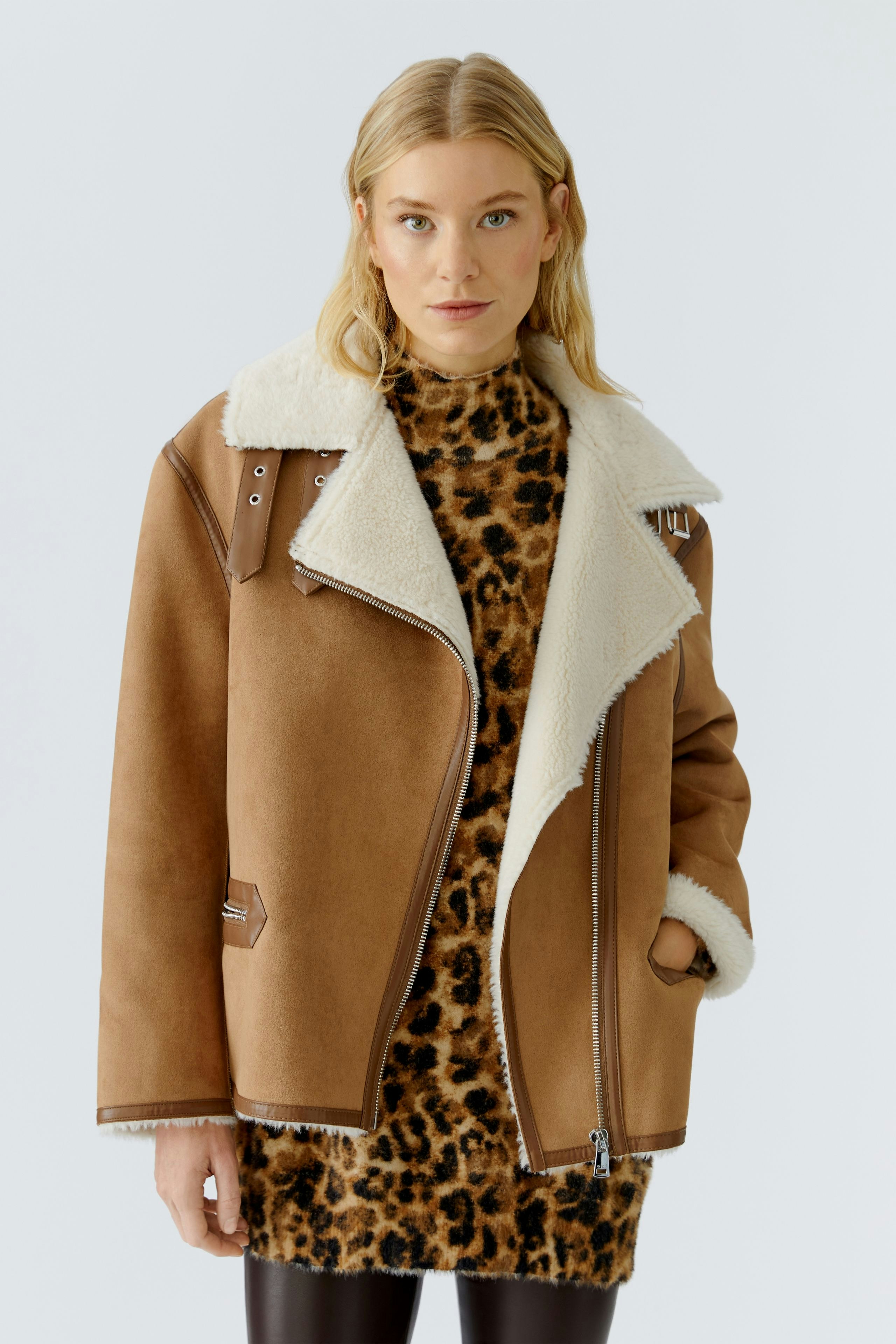 Stylish women's outdoor jacket: A woman in a brown jacket with a fluffy collar, paired with a leopard print dress.