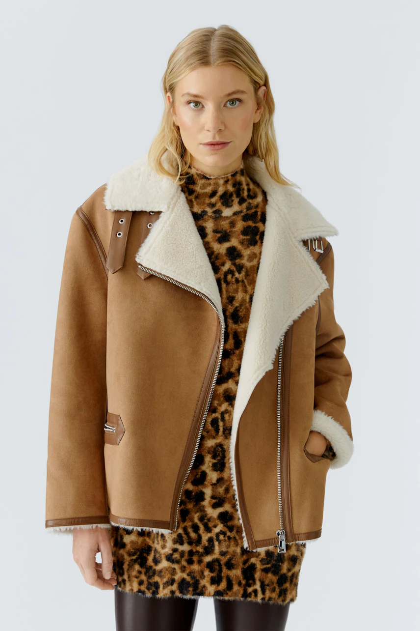 Stylish women's outdoor jacket: A woman in a brown jacket with a fluffy collar, paired with a leopard print dress.