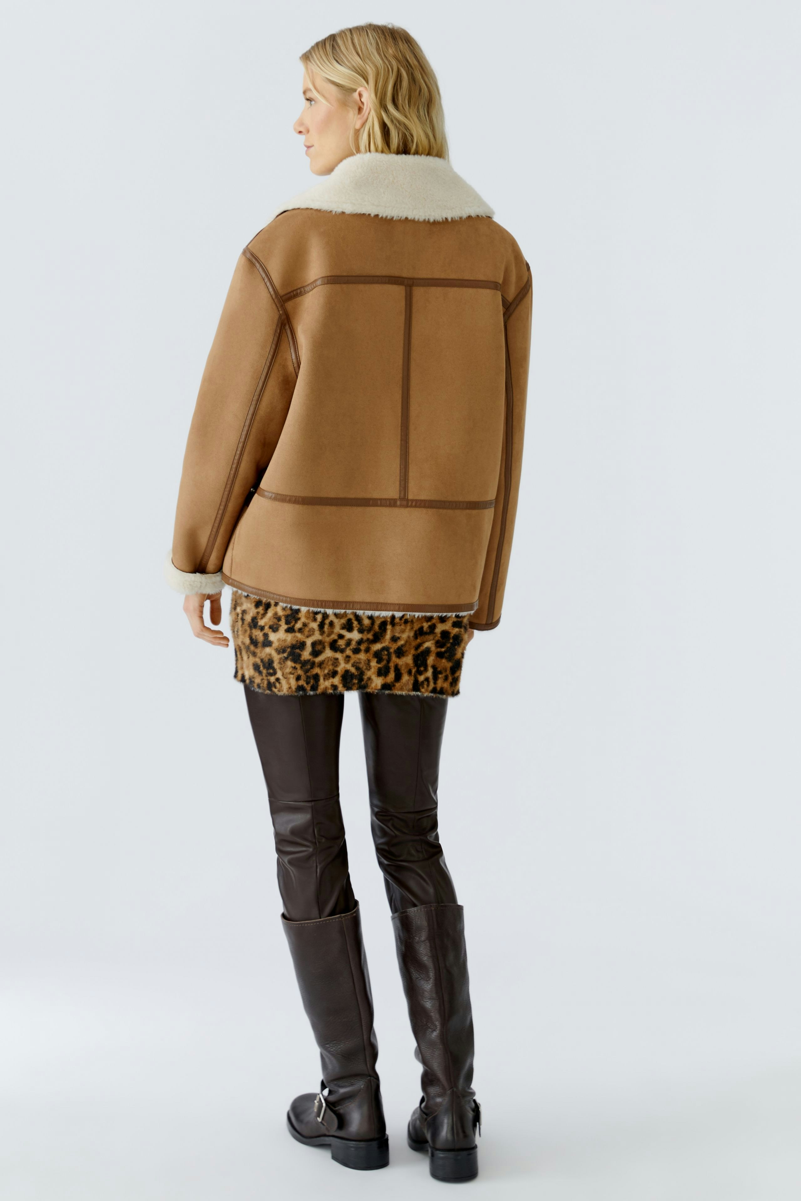 Stylish outdoor jacket: Woman in a brown jacket with a cozy collar, paired with a leopard print skirt.