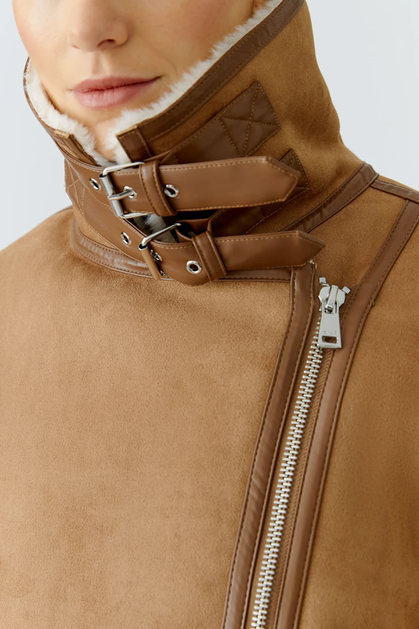 Stylish women's outdoor jacket: Close-up of a woman in a brown jacket with a high collar and zipper.