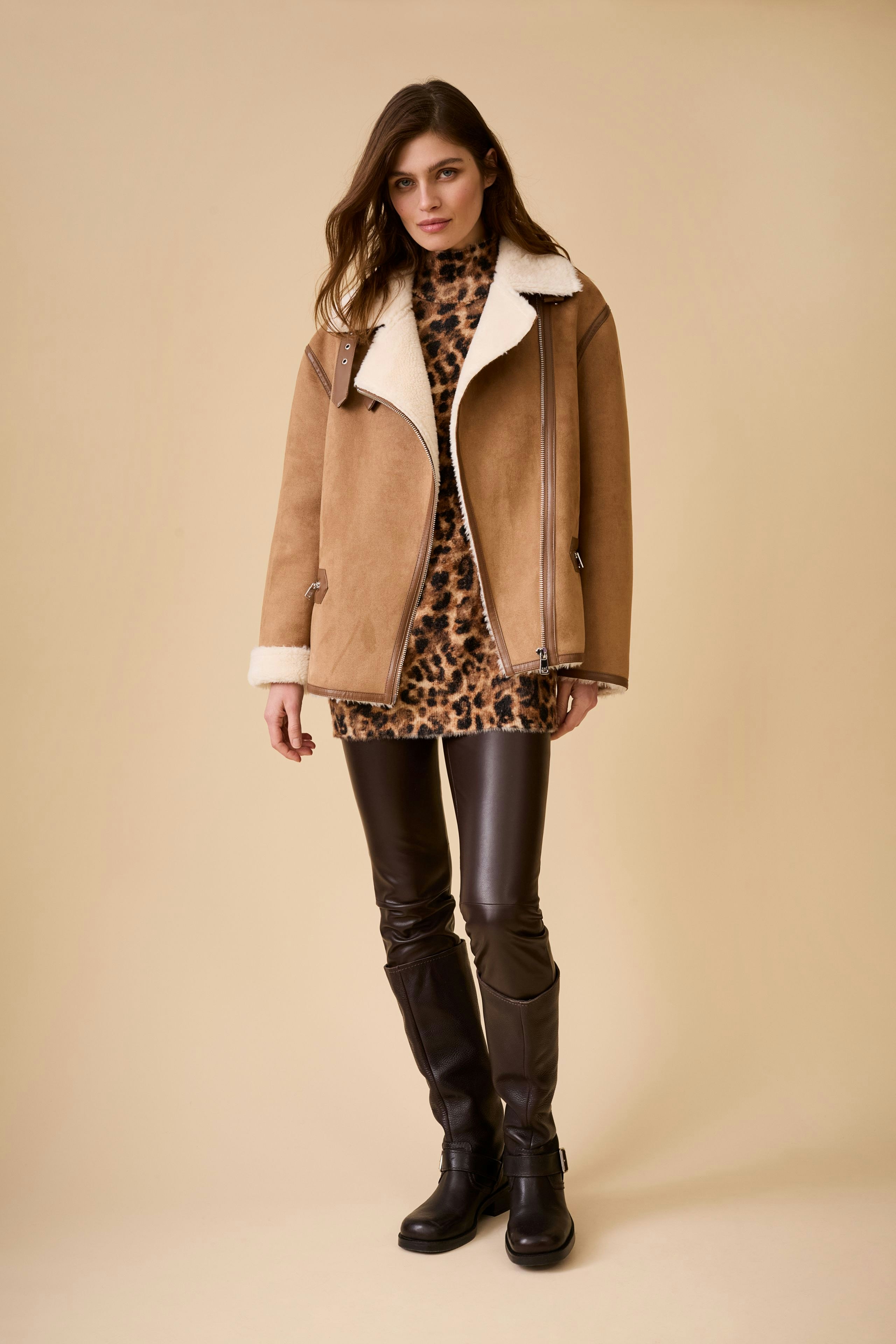 Stylish women's outdoor jacket: A woman in a tan jacket with a cozy collar, paired with a leopard print dress.