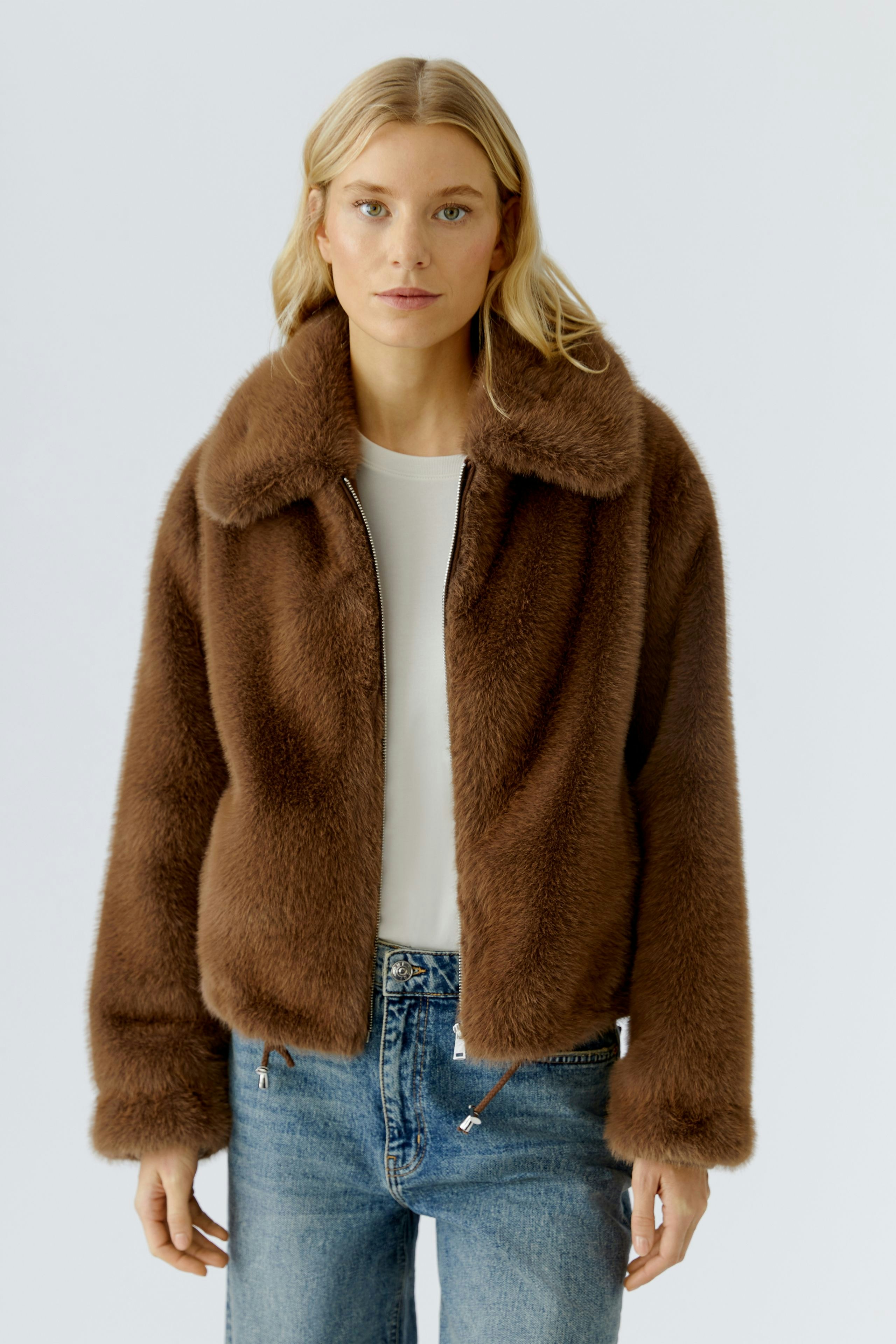 Cozy women's jacket: A woman in a brown fluffy jacket paired with jeans, exuding a relaxed vibe.