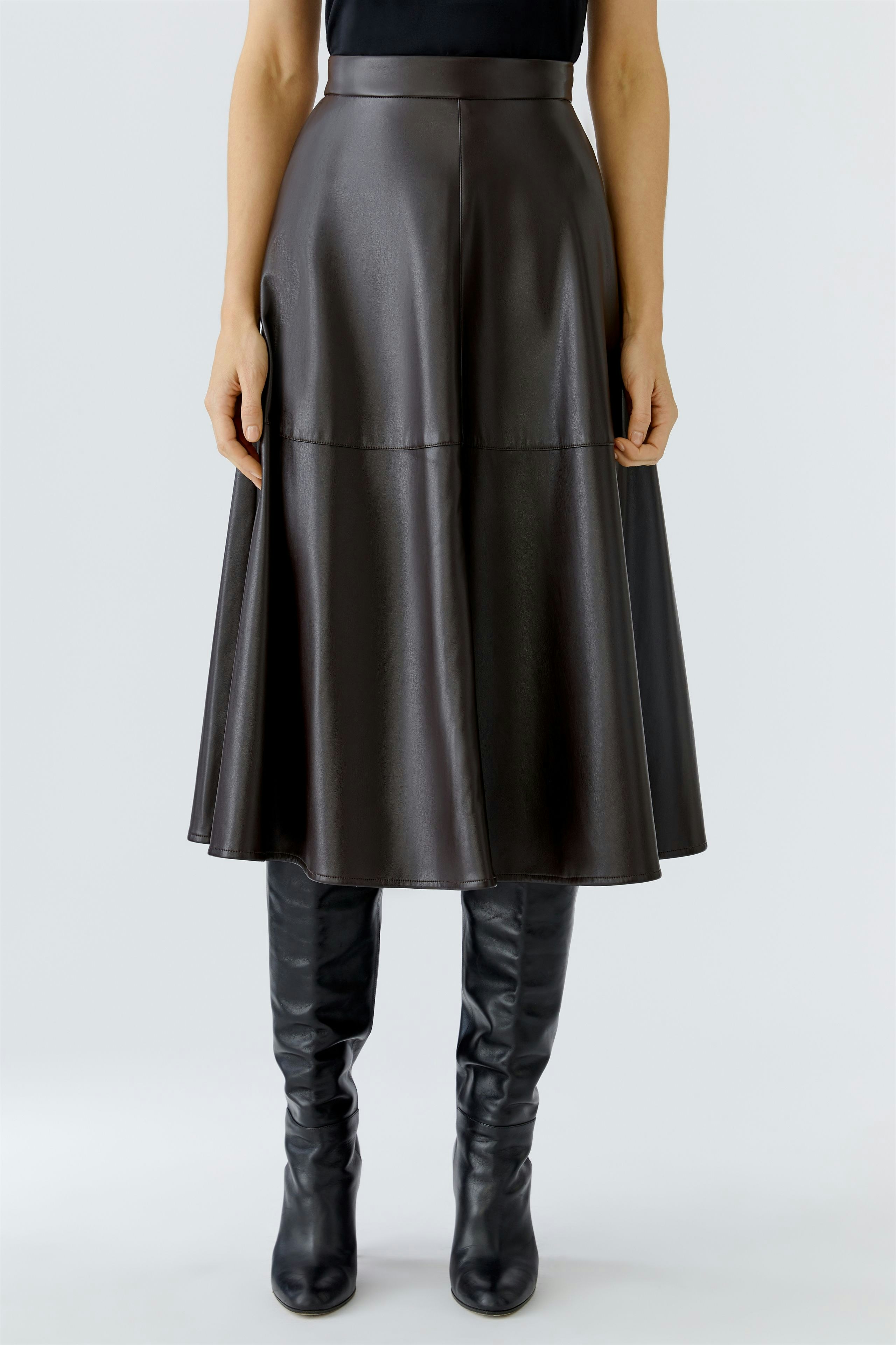 A-line skirt: Woman in a brown faux leather skirt paired with knee-high black boots.