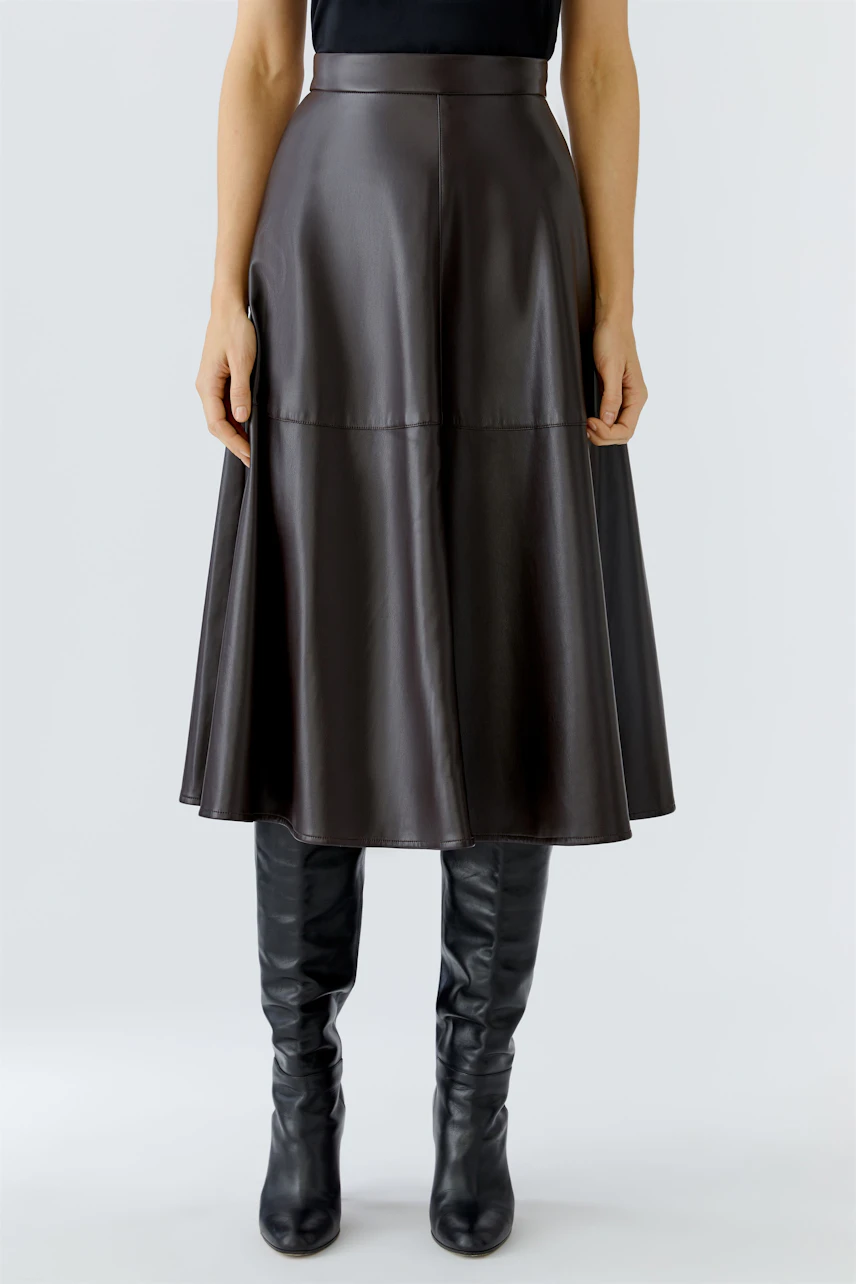 A-line skirt: Woman in a brown faux leather skirt paired with knee-high black boots.