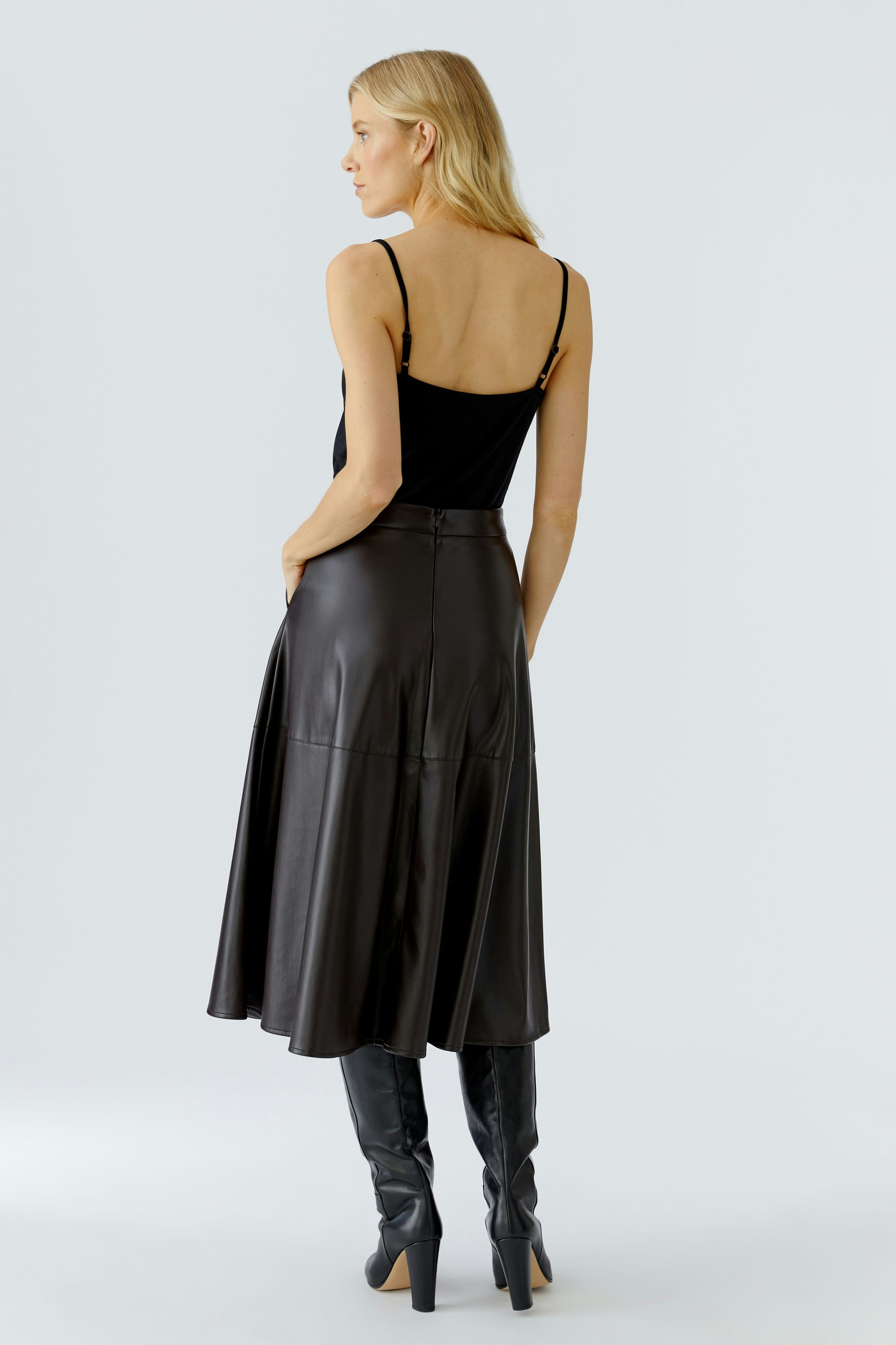 A-line skirt: Woman in a black leather skirt, showcasing a modern and stylish look.