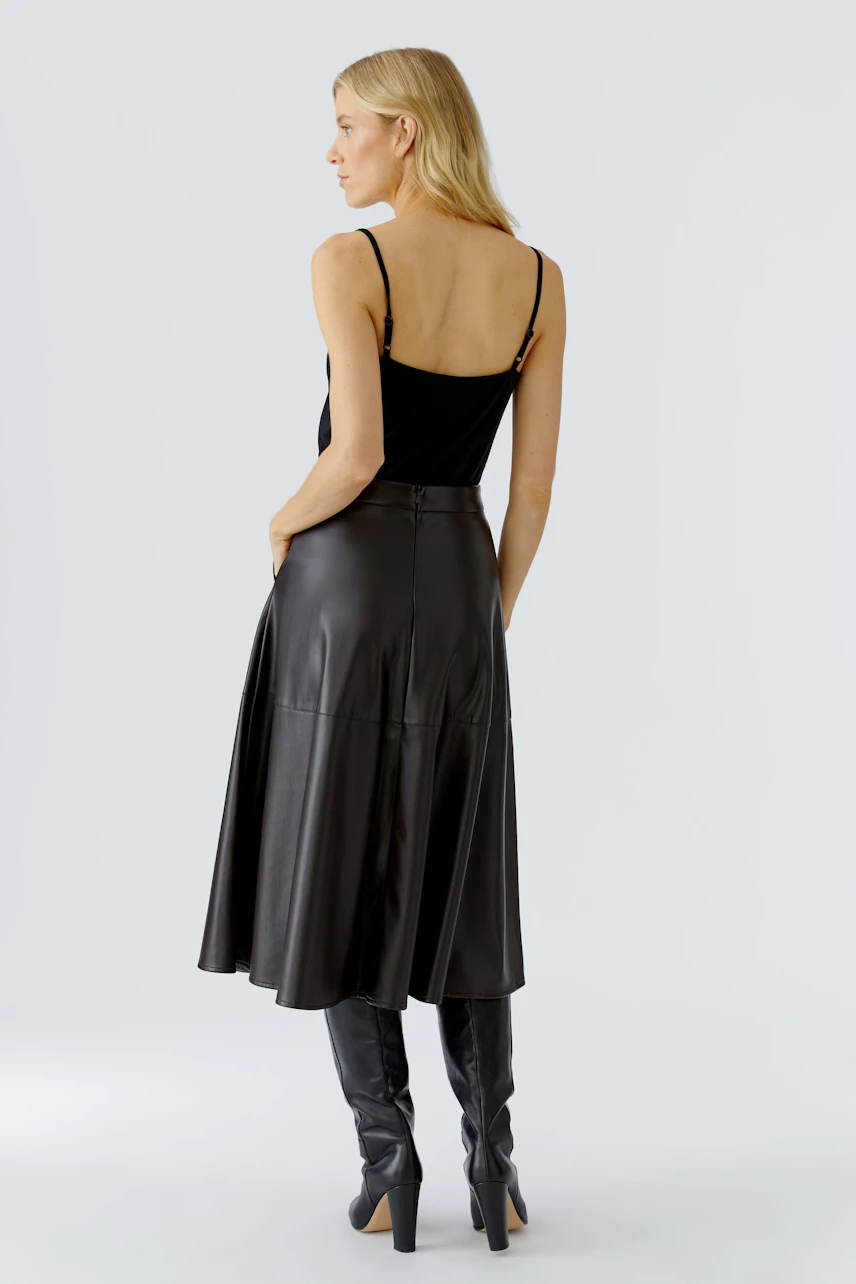 A-line skirt: Woman in a black leather skirt, showcasing a modern and stylish look.