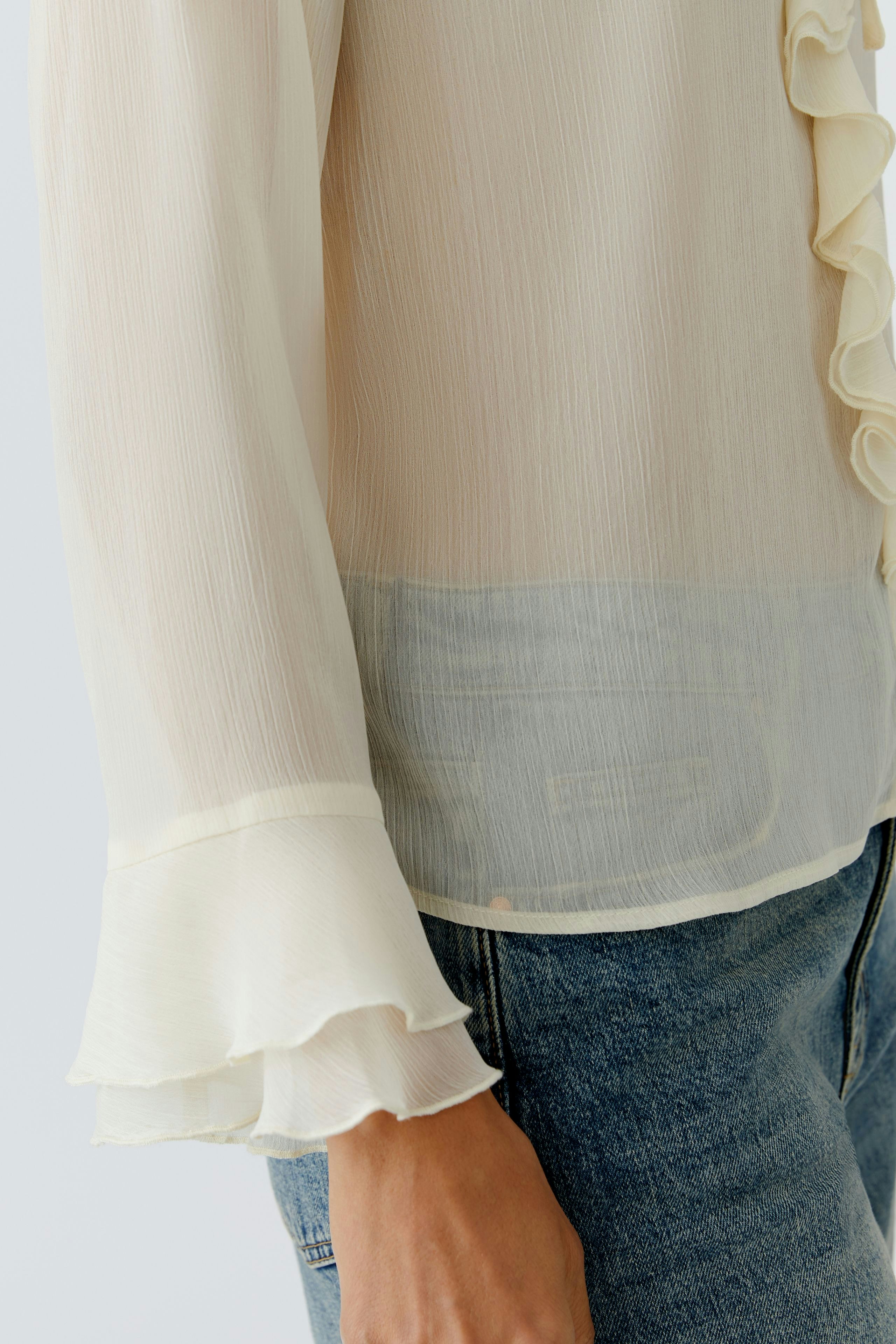 Light blouse: Woman in a soft, ruffled blouse with flared sleeves, paired with casual jeans.