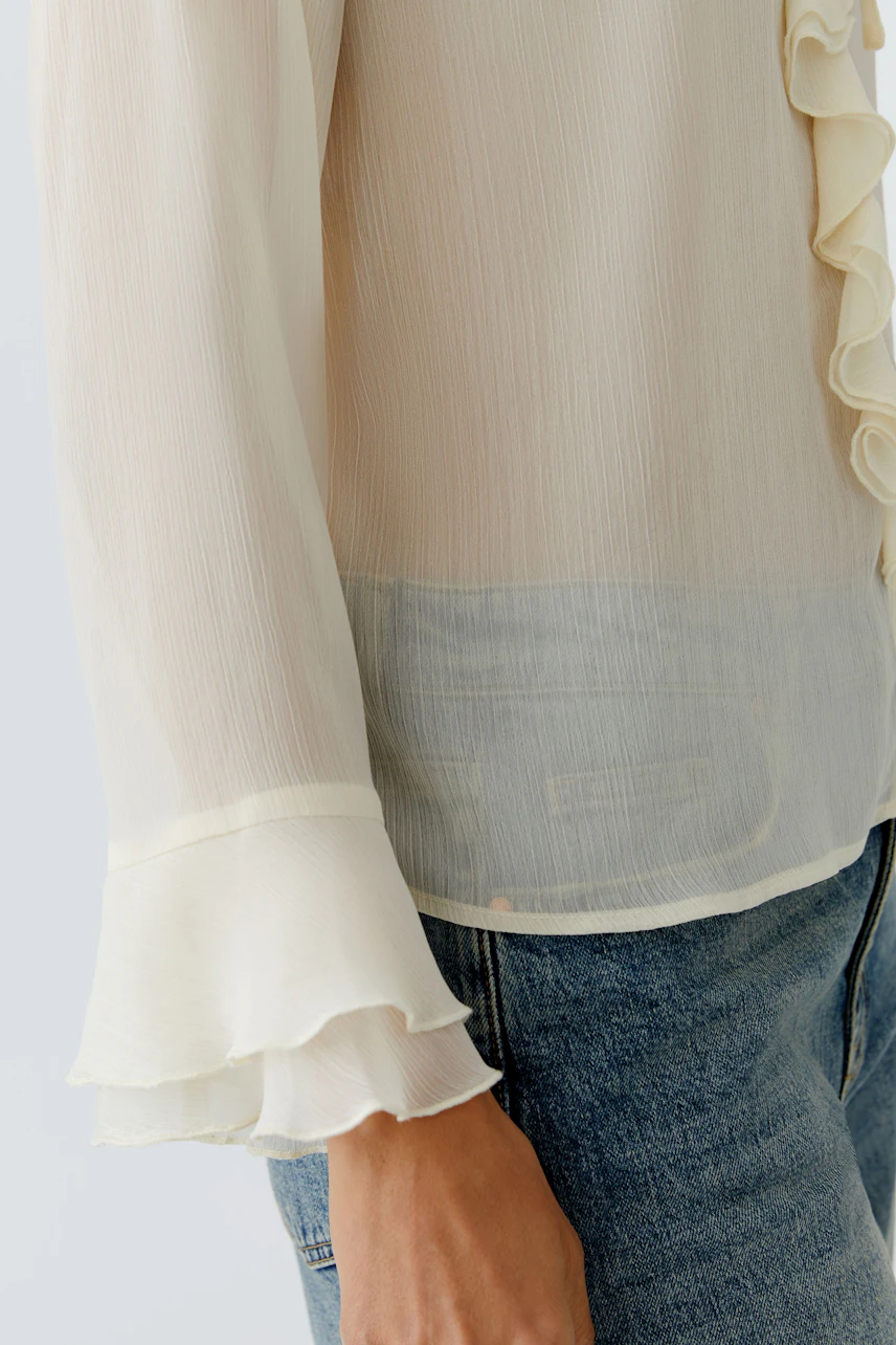 Light blouse: Woman in a soft, ruffled blouse with flared sleeves, paired with casual jeans.