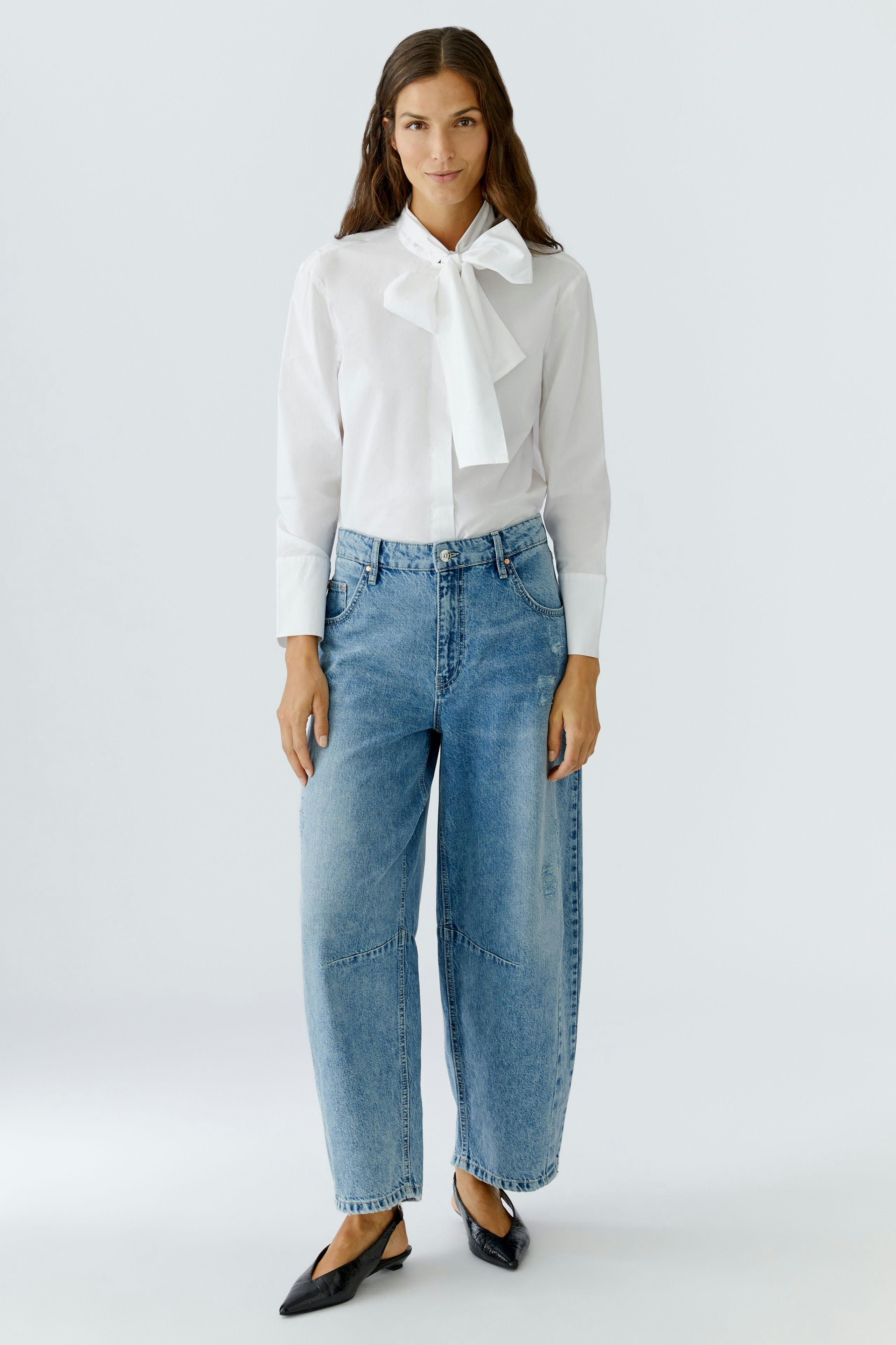 White blouse with a bow tie: Woman wearing a stylish blouse paired with relaxed-fit jeans.