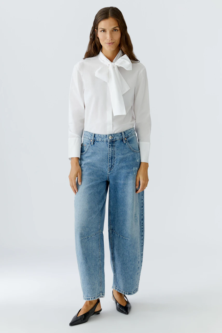 White blouse with a bow tie: Woman wearing a stylish blouse paired with relaxed-fit jeans.