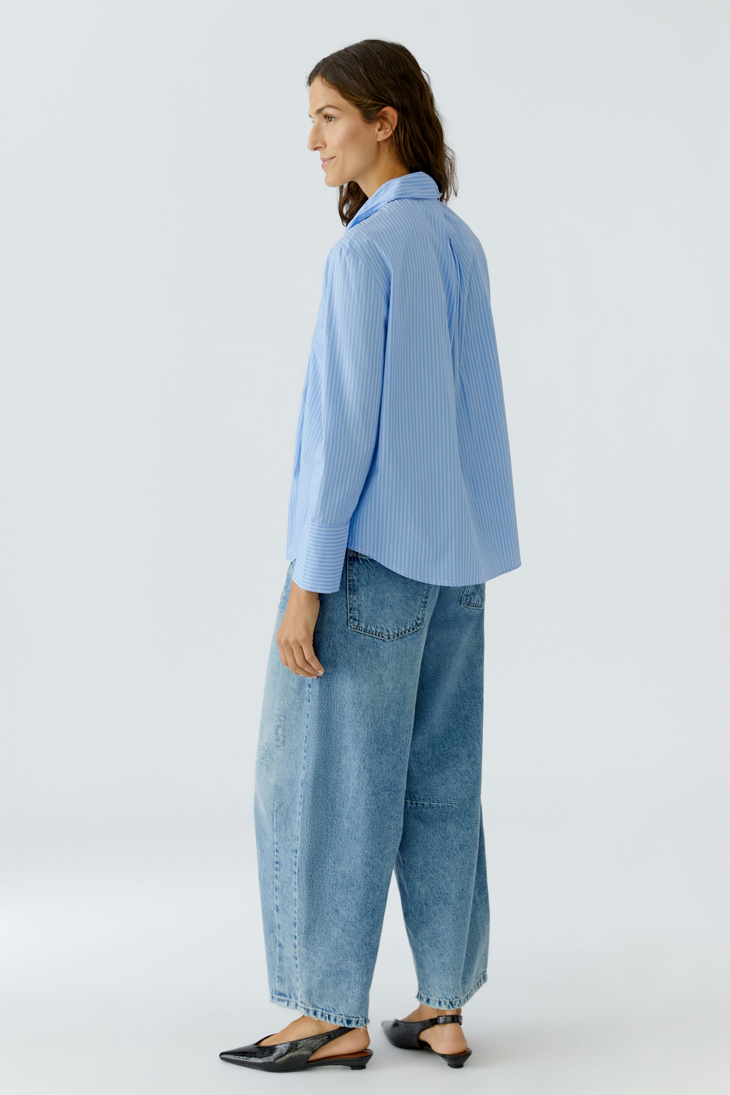 Casual women's blouse: Woman in a light blue striped blouse paired with relaxed-fit jeans.