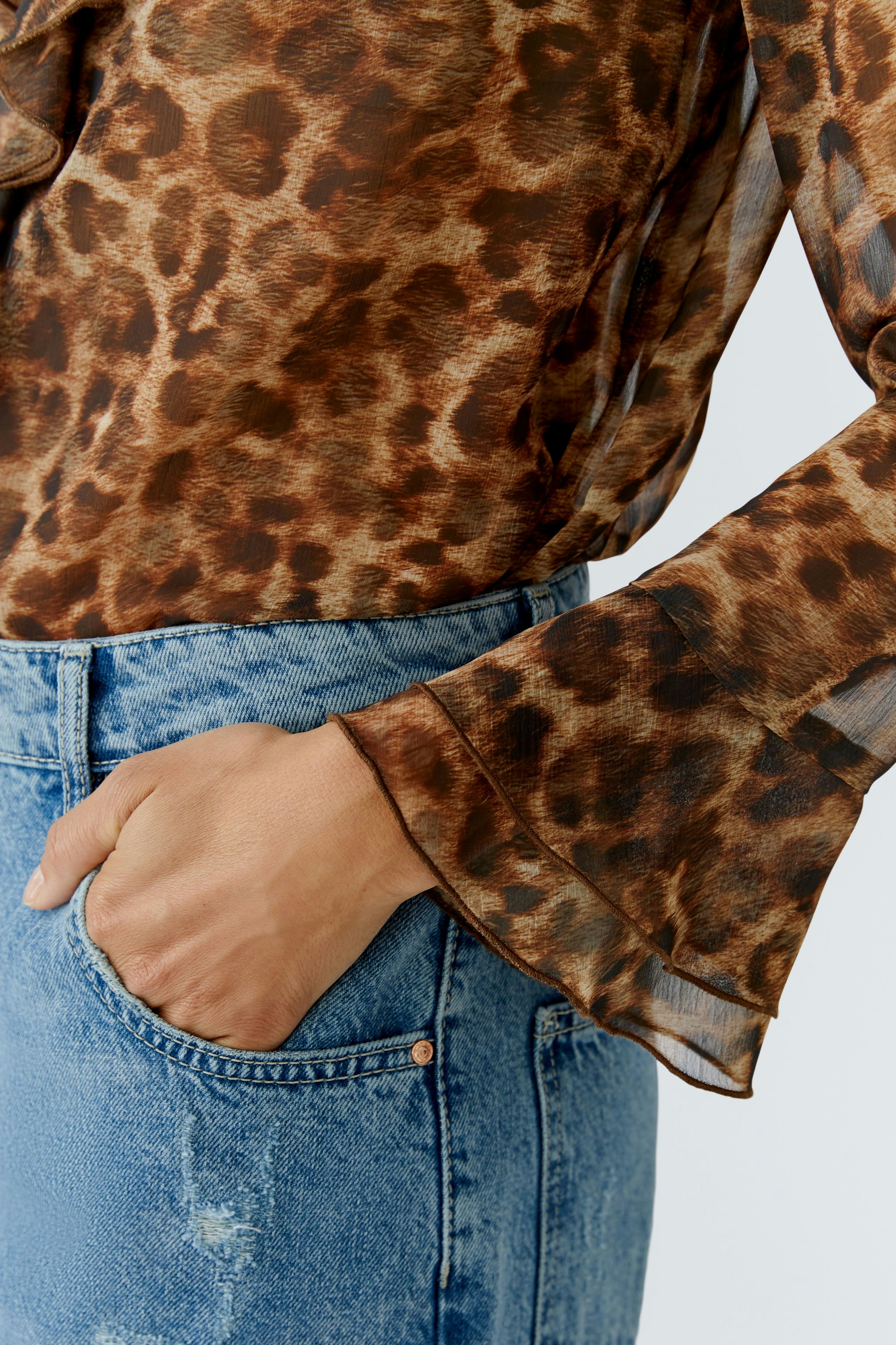 Stylish women's blouse: Close-up of a woman in a brown leopard print blouse with flared sleeves.
