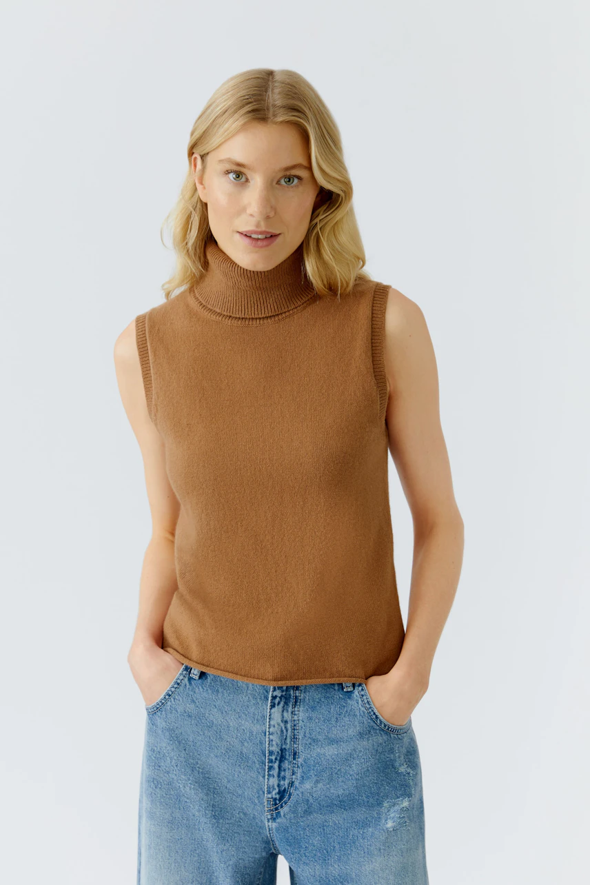 Casual women's top: Young woman in a brown sleeveless turtleneck top paired with blue jeans.