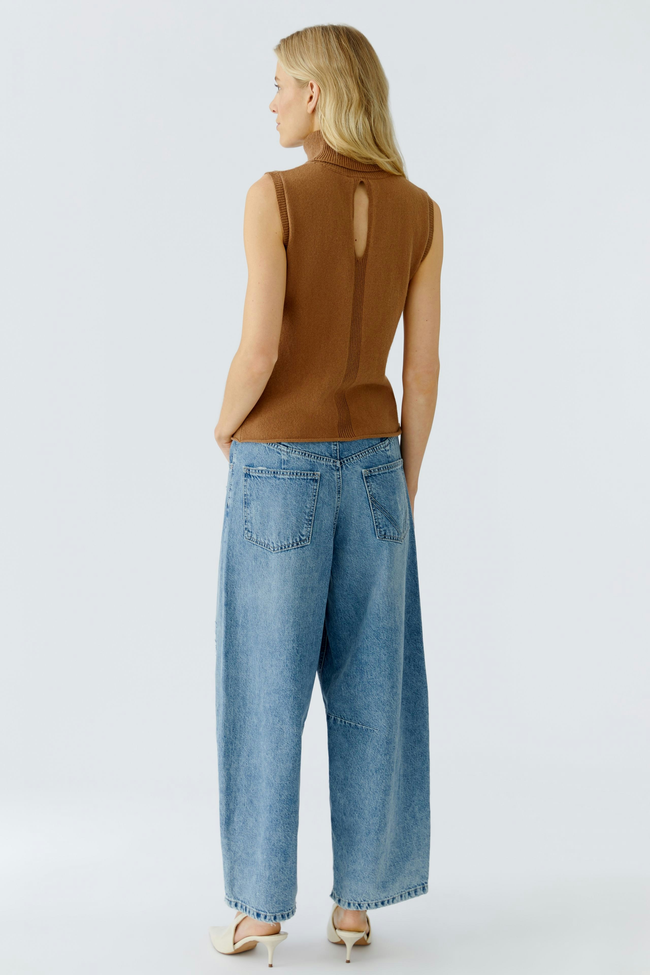Casual women's top: A woman in a brown sleeveless top with a keyhole back and relaxed fit jeans.