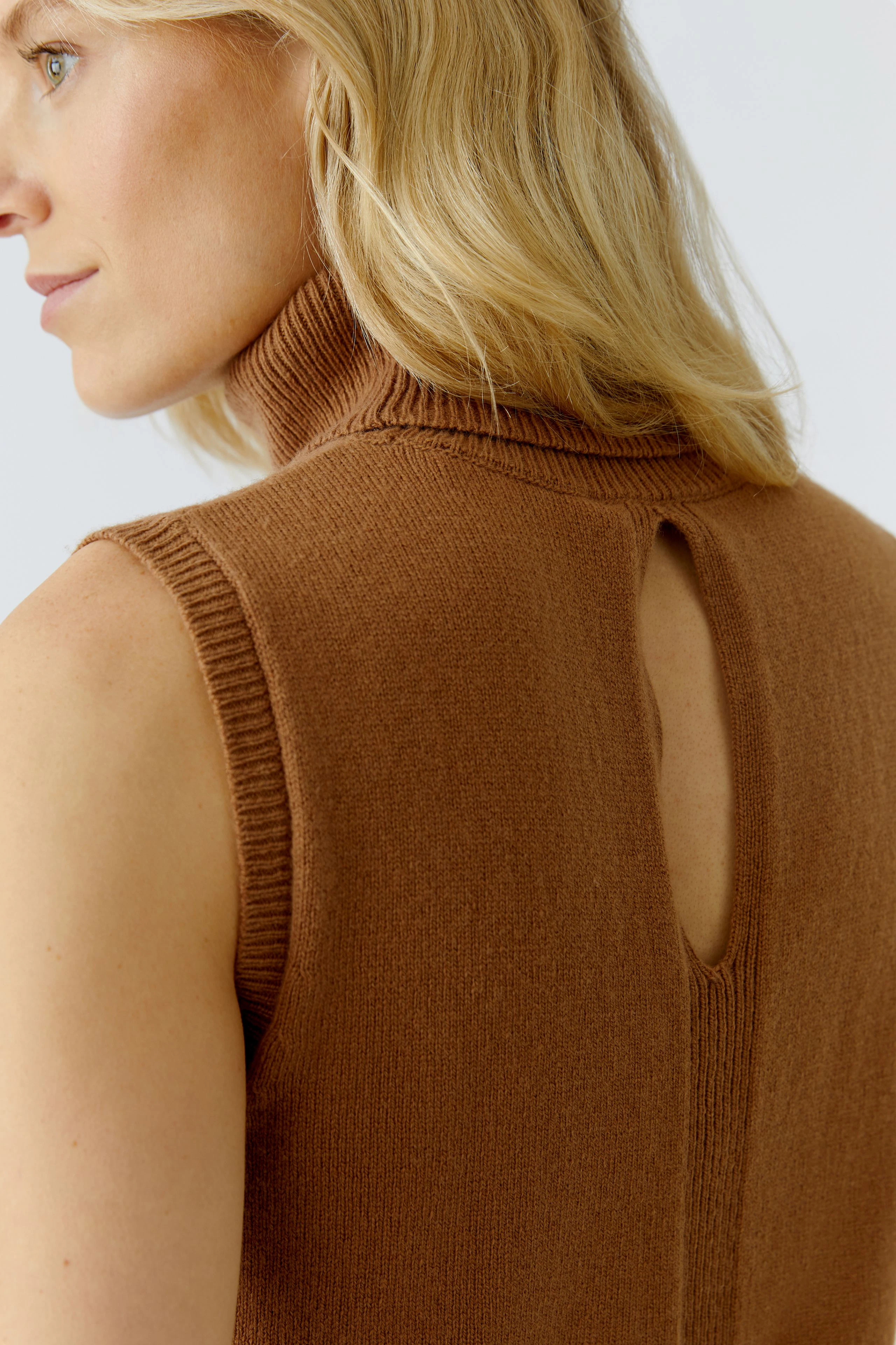 Damen-Top: Frau mit braunem, ärmellosem Stricktop mit Stehkragen und Rückenausschnitt.