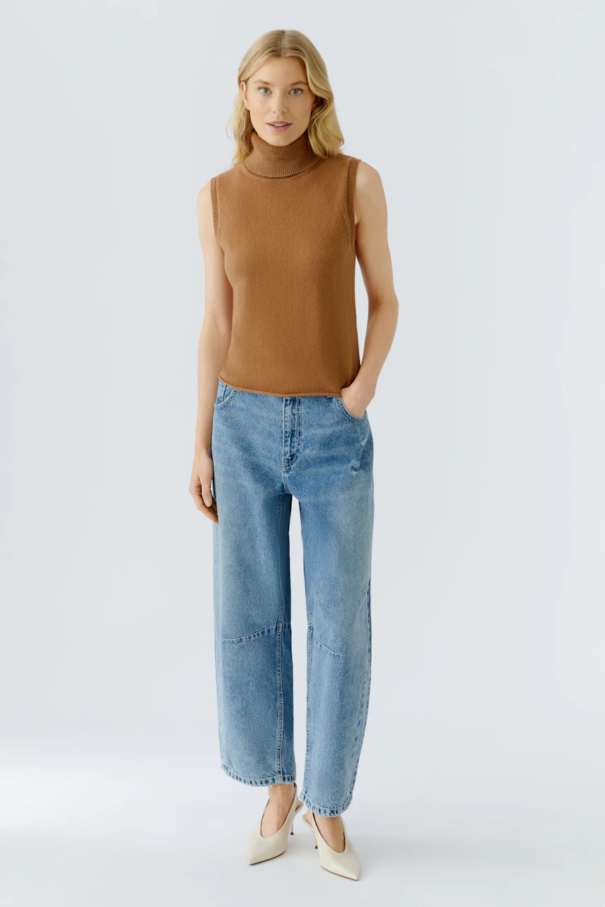 Casual women's top: A woman in a brown sleeveless top paired with wide blue jeans stands confidently.