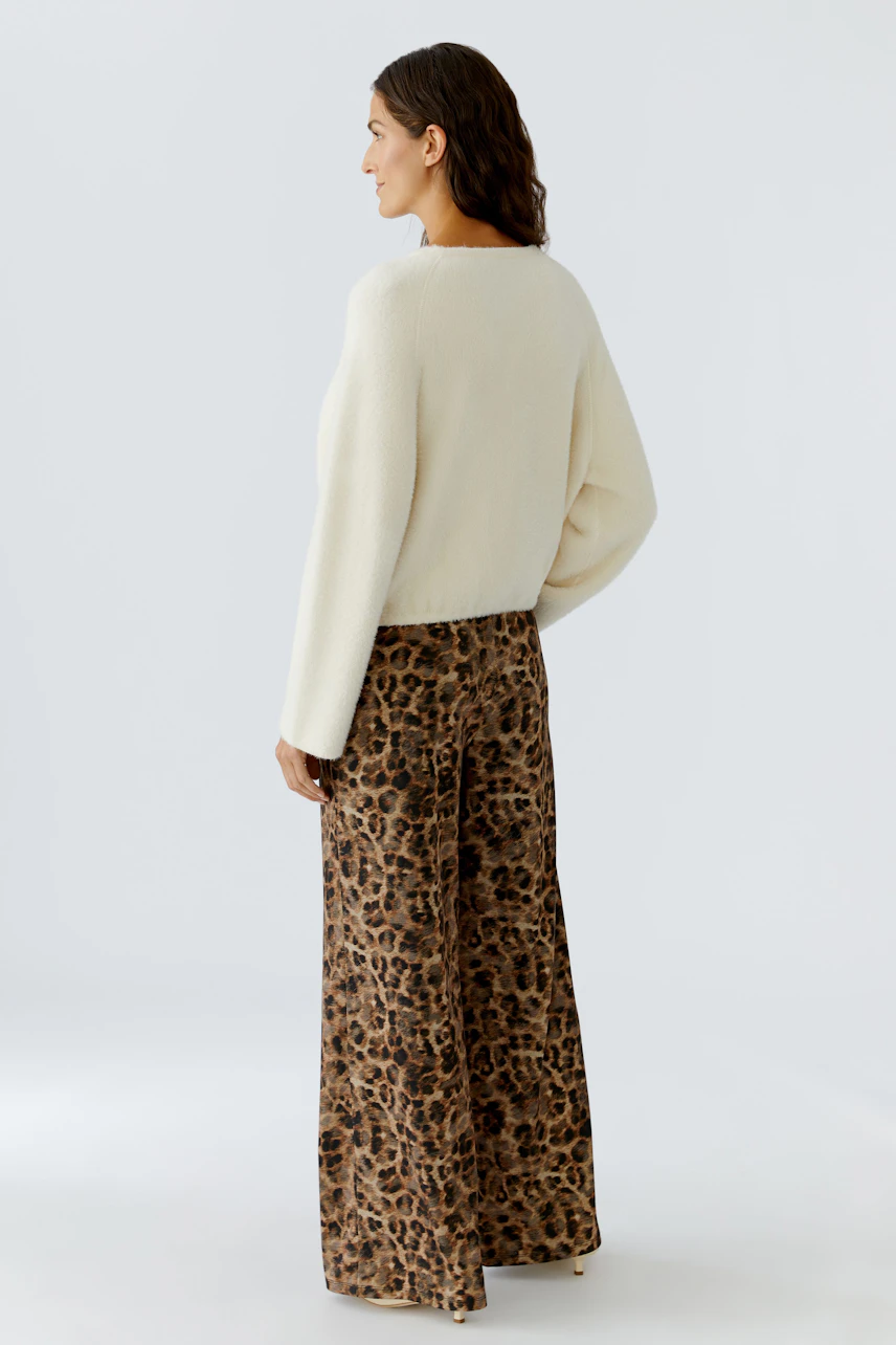 Damen-Pullover: Frau in einem weißen, lässigen Pullover mit weitem Schnitt und animalischem Print.