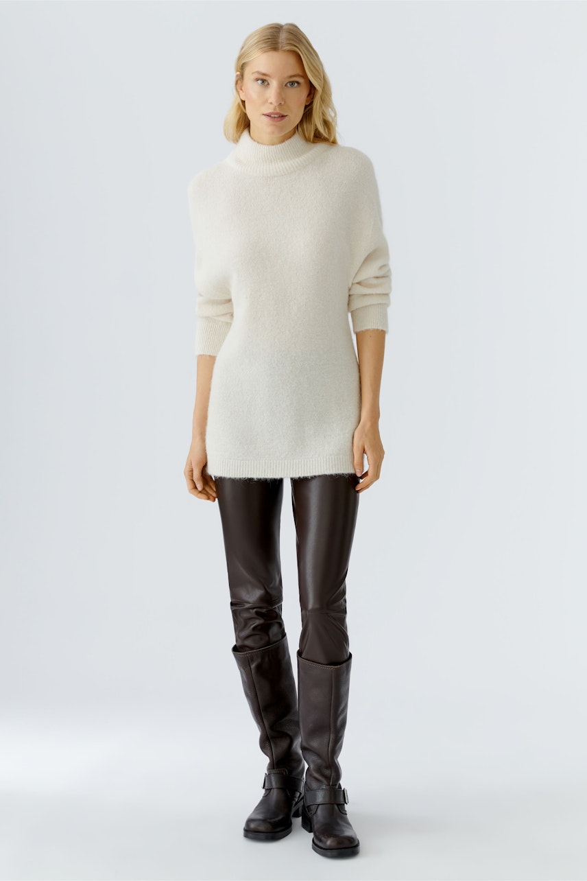 Bequemer Damen-Pullover in Cremefarbe, lässig geschnitten, kombiniert mit schwarzen Lederhosen.