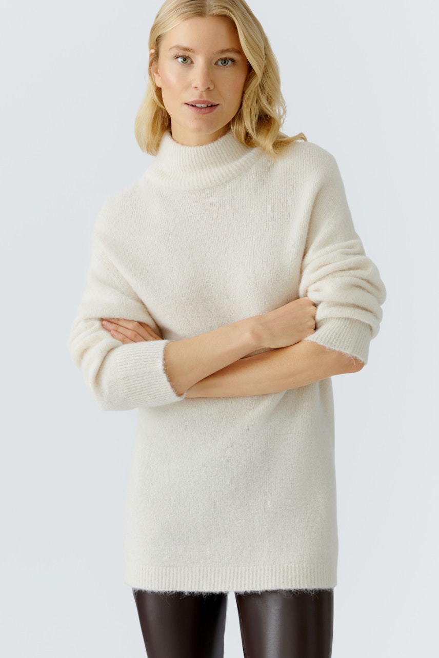 Damen-Pullover: Frau in hellem, weichem Pullover mit hohem Kragen und lässigem Schnitt.
