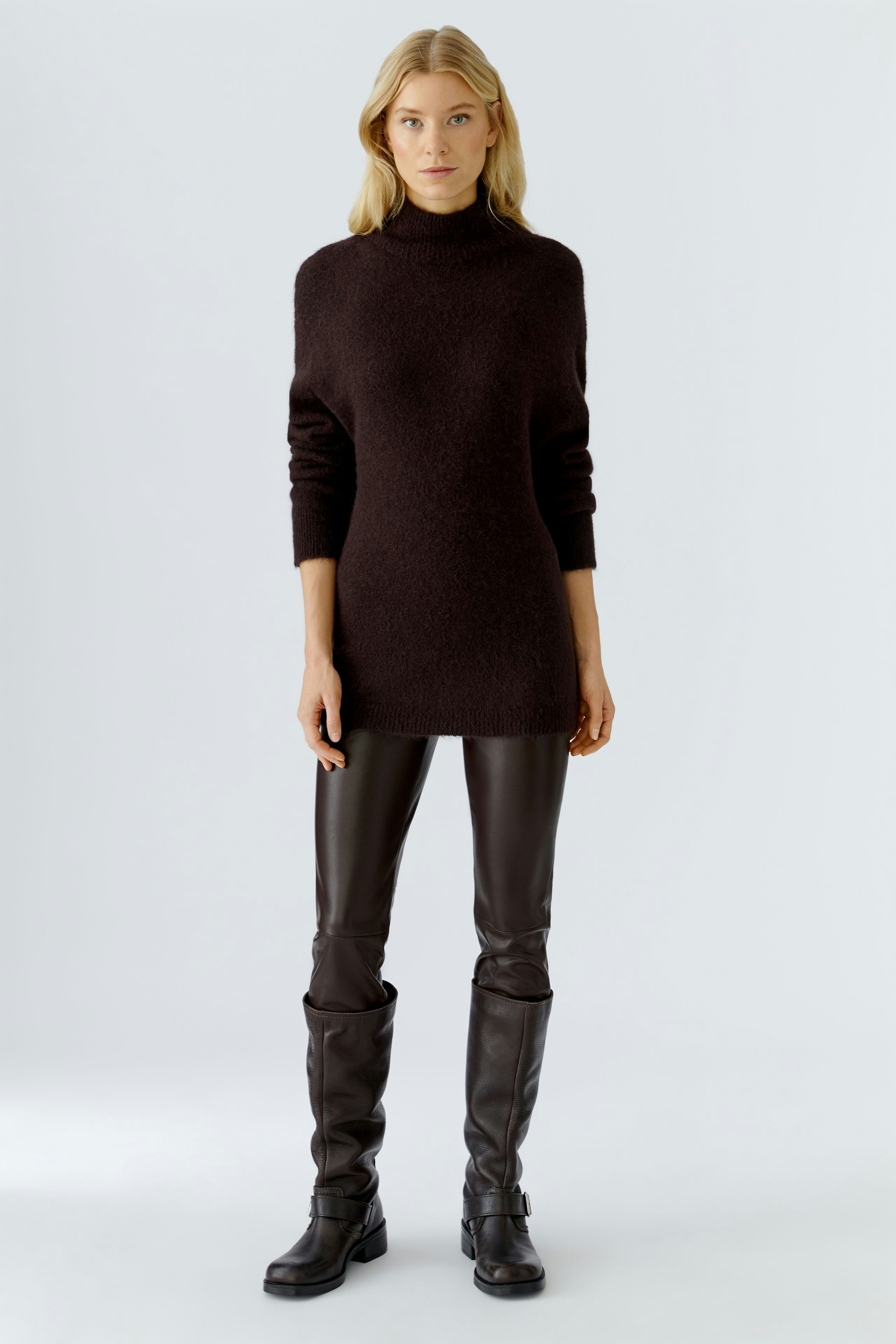 Casual women's pullover: A woman in a dark brown pullover with a high neck, paired with sleek leather pants.
