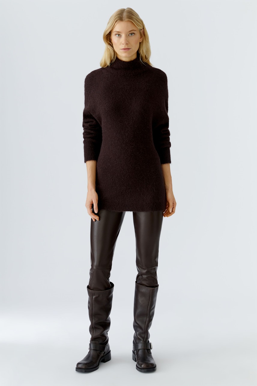 Damen-Pullover: Junge Frau in einem braunen, lässigen Strickpullover mit hohem Kragen und schmalen Hosen.
