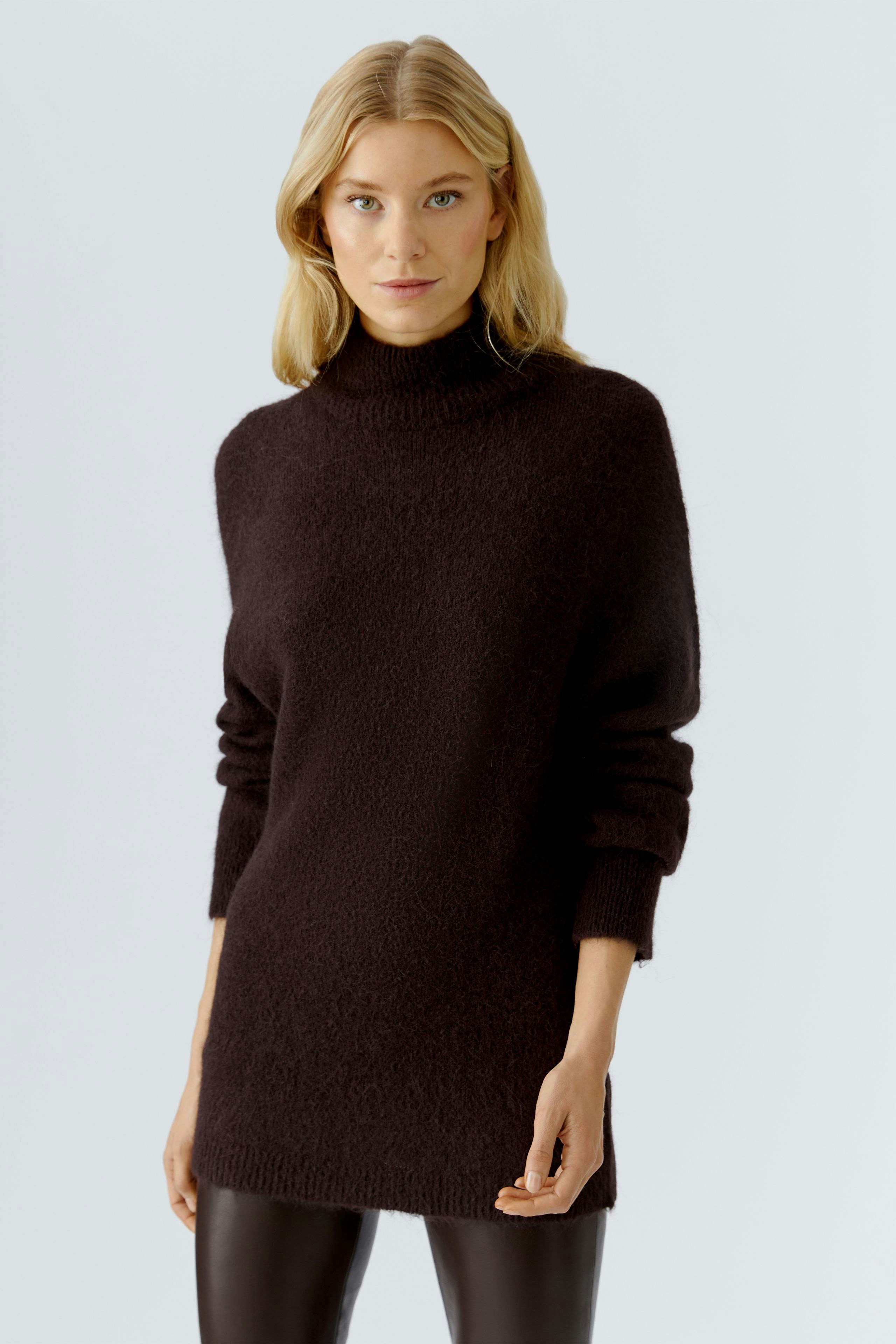 Cozy women's pullover: A woman in a dark, soft pullover with a high neck and relaxed fit.