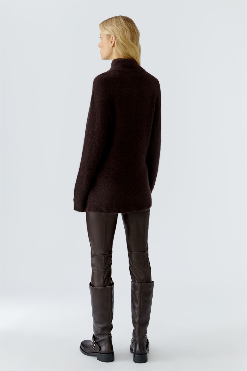 Damen-Pullover: Frau mit braunem, weichem Pullover und lässigen, braunen Lederhosen von hinten.