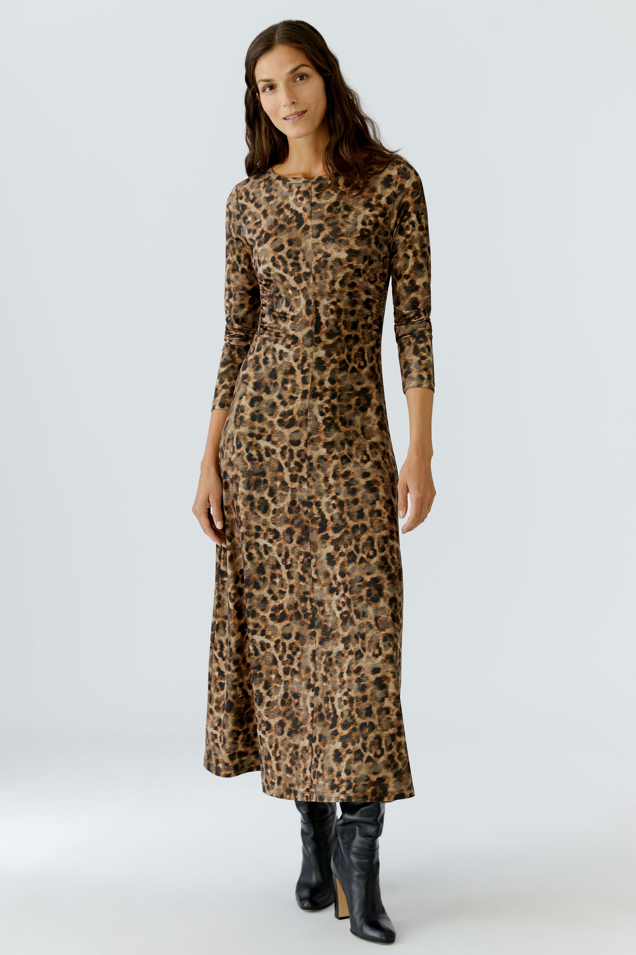Casual women's dress: A woman in a long, leopard-print dress with three-quarter sleeves stands confidently.