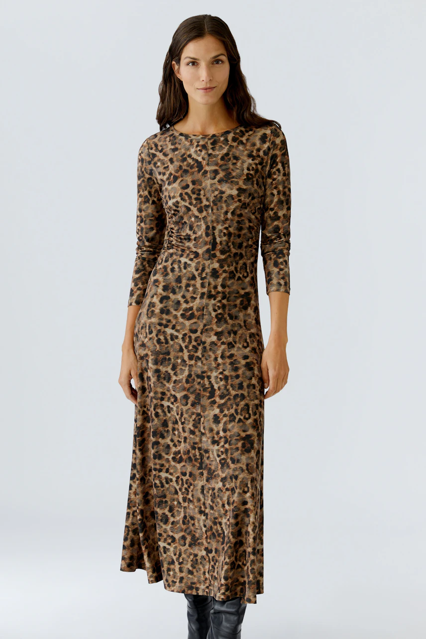 Leopard print dress: Woman in a long-sleeve, fitted dress with a stylish animal pattern.