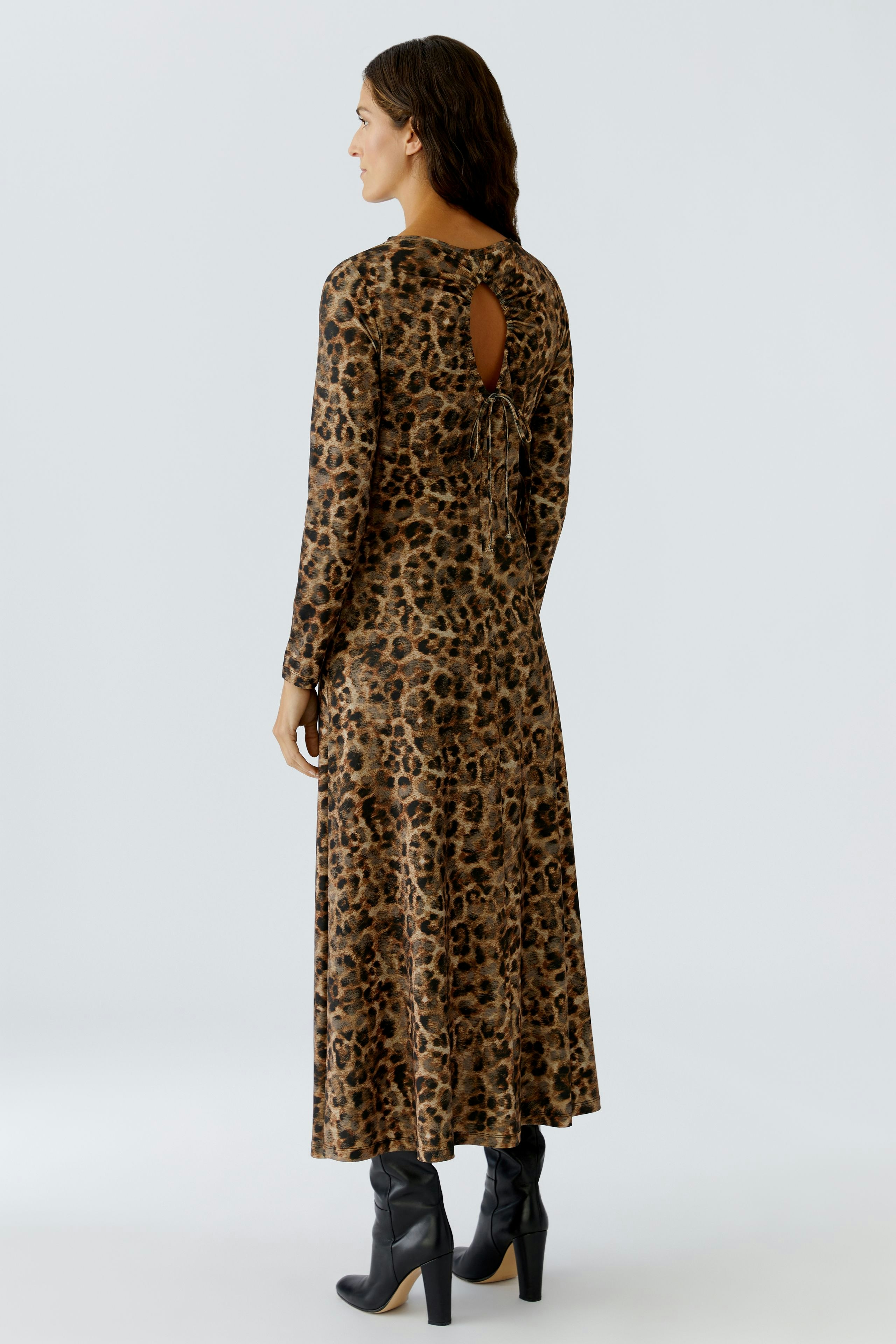 Leopard print dress: Woman in a long-sleeve dress with a back tie detail and stylish boots.