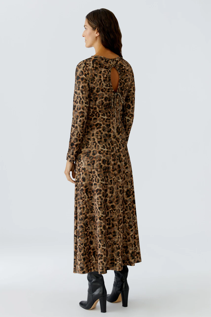 Leopard print dress: Woman in a long-sleeve dress with a back tie detail and stylish boots.