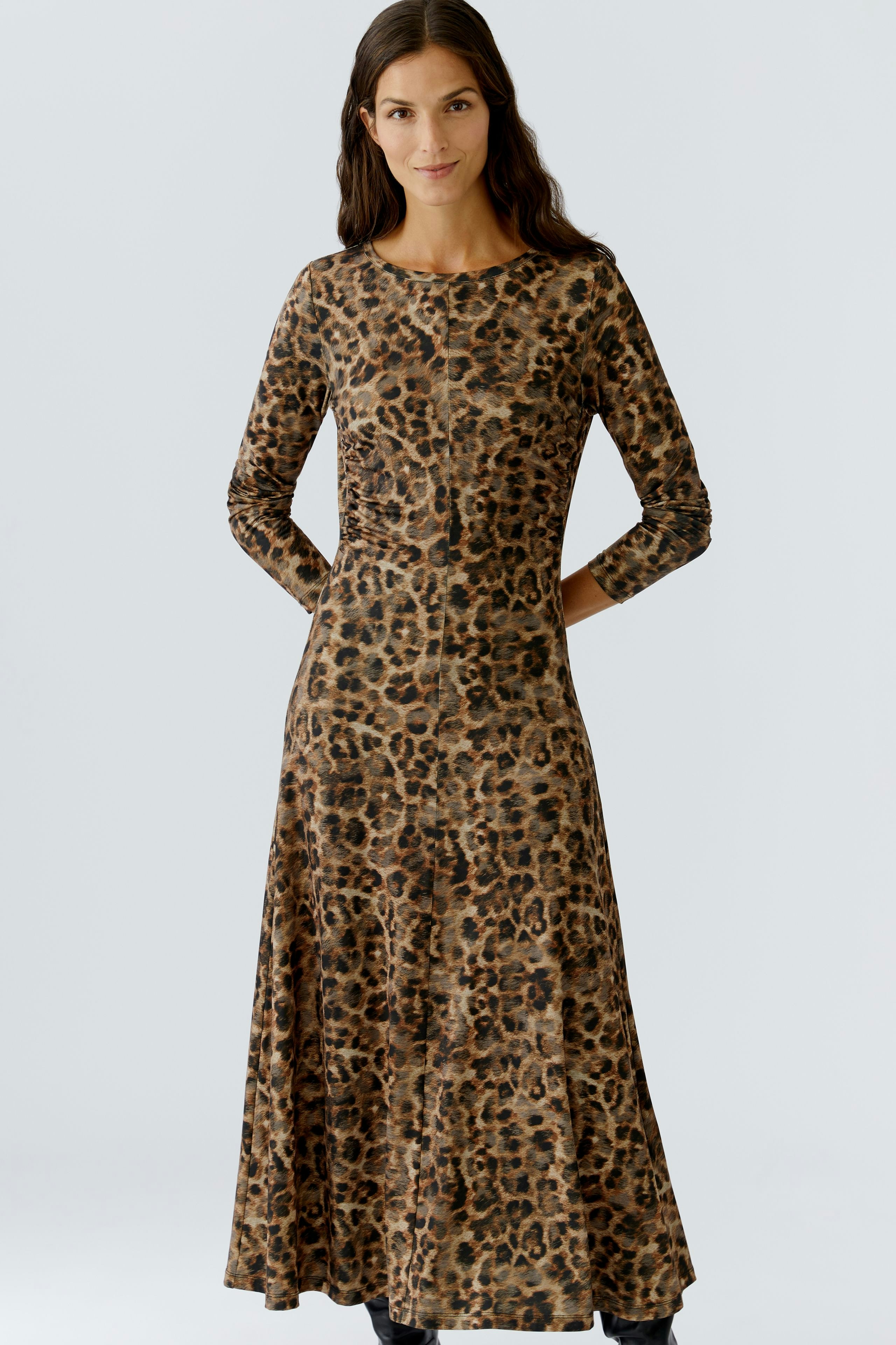 Leopard print dress: Woman in a long-sleeve, fitted dress with a flowing skirt and round neckline.