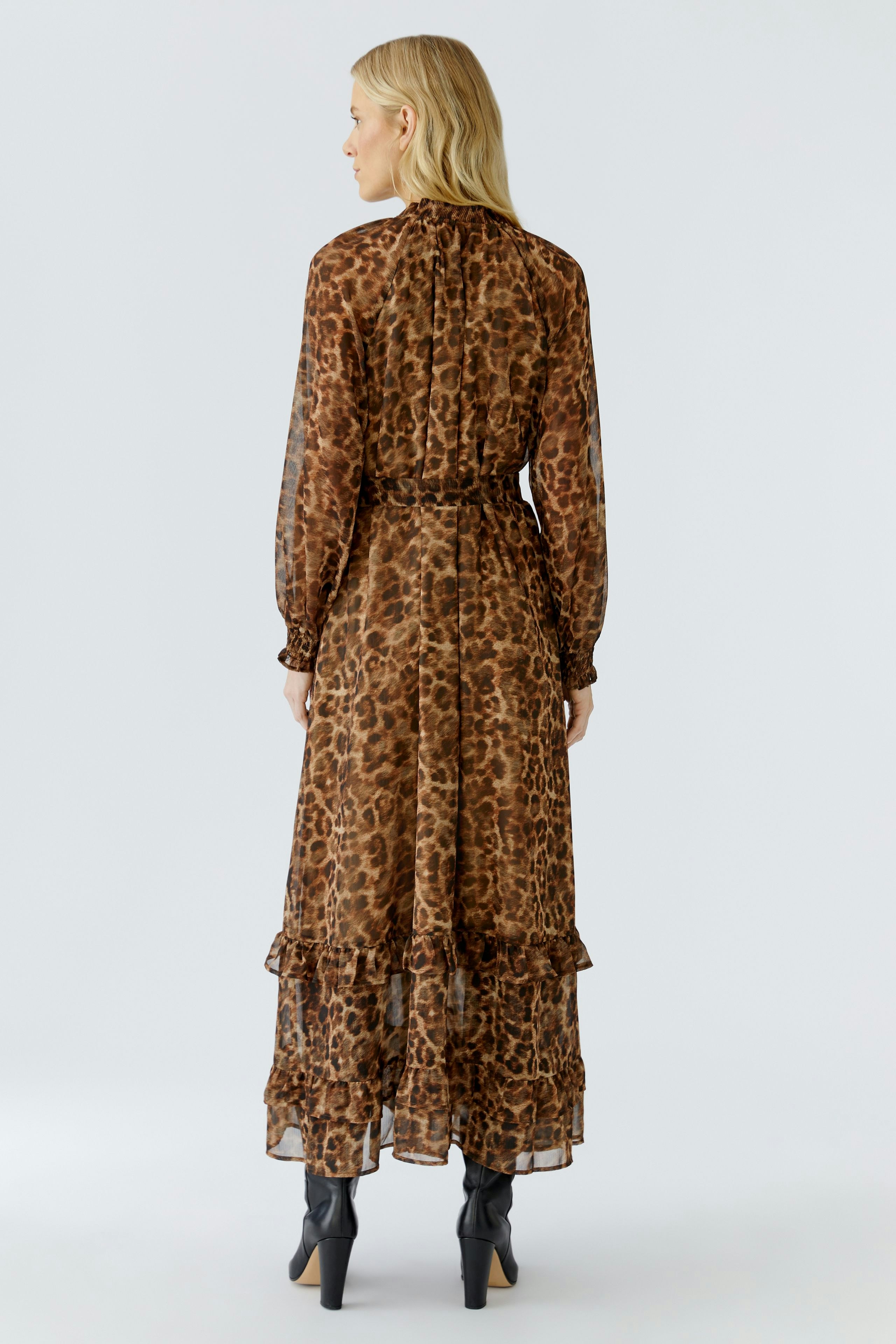 Stylish maxi dress: Woman in a brown leopard print dress with long sleeves and tiered hem.