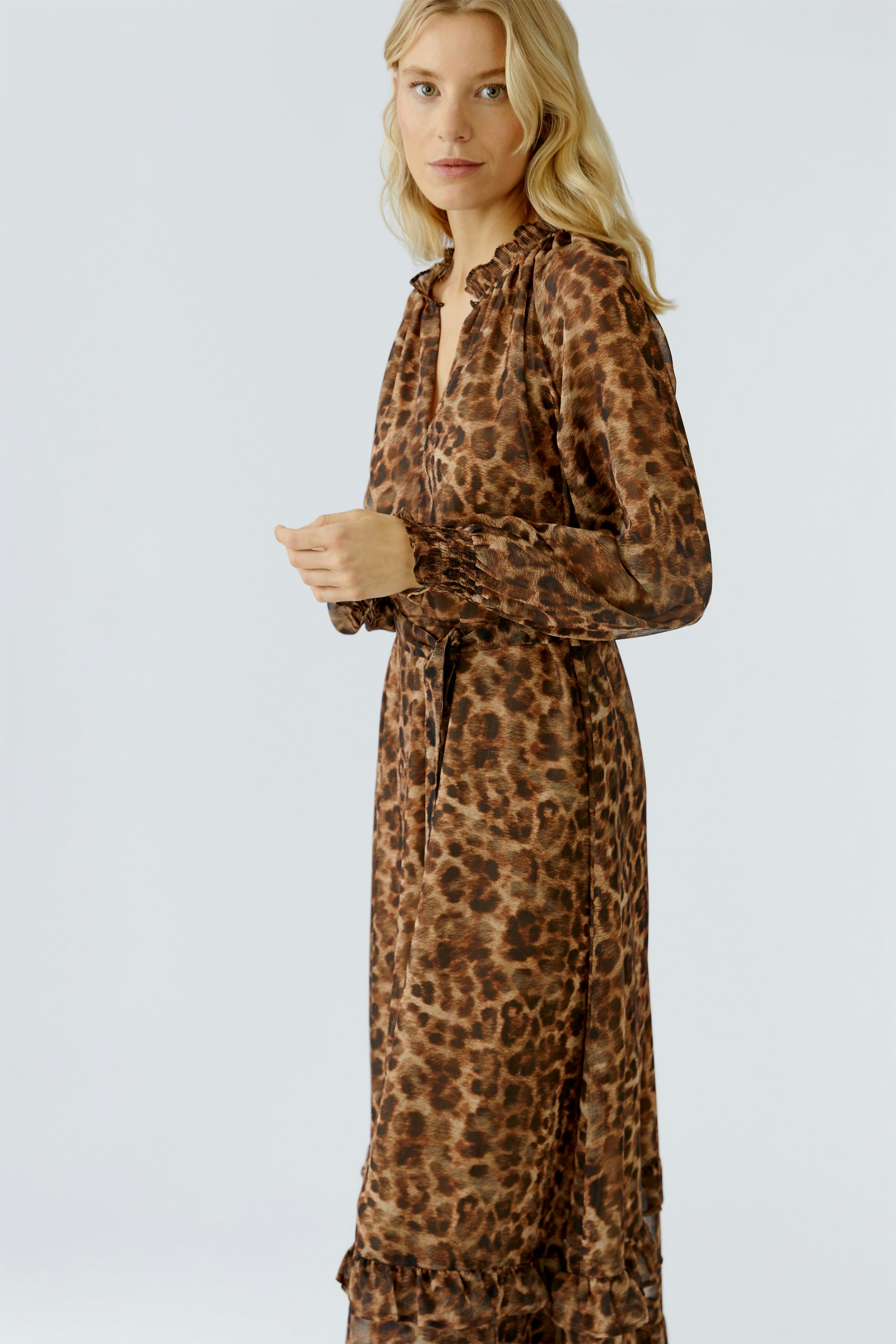Leopard print maxi dress: Woman in a long, flowing dress with a ruffled neckline and tie waist.