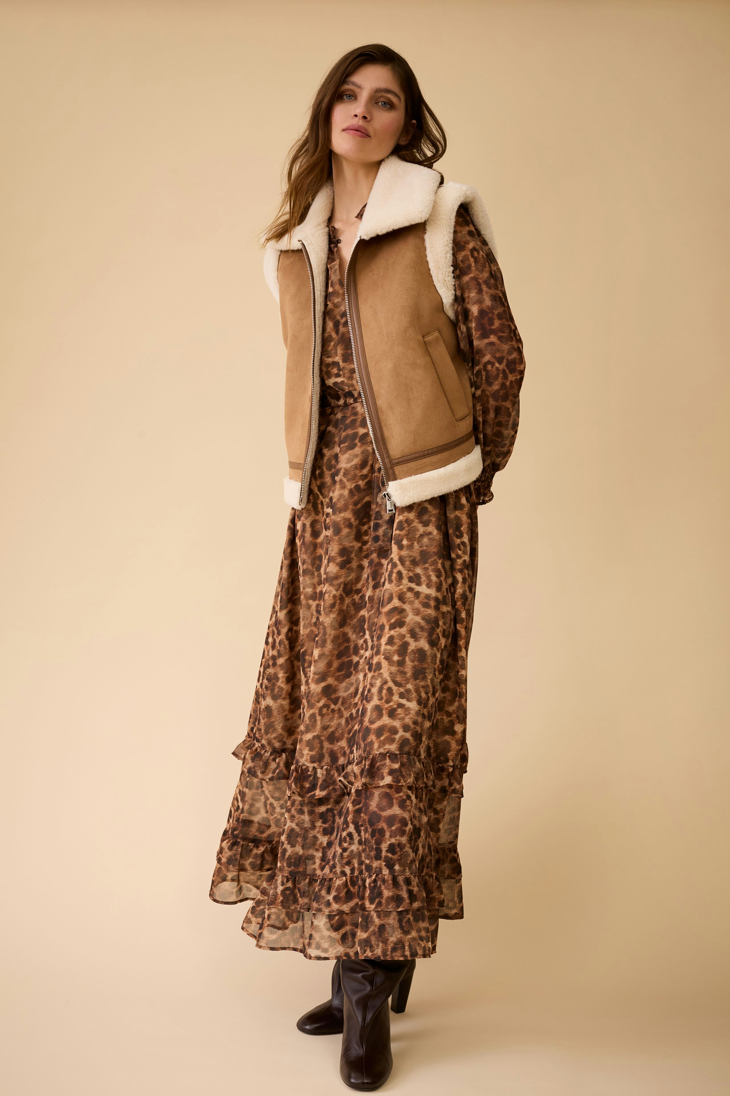 Maxi dress: Woman in a brown leopard print maxi dress with a cozy vest, showcasing a relaxed style.