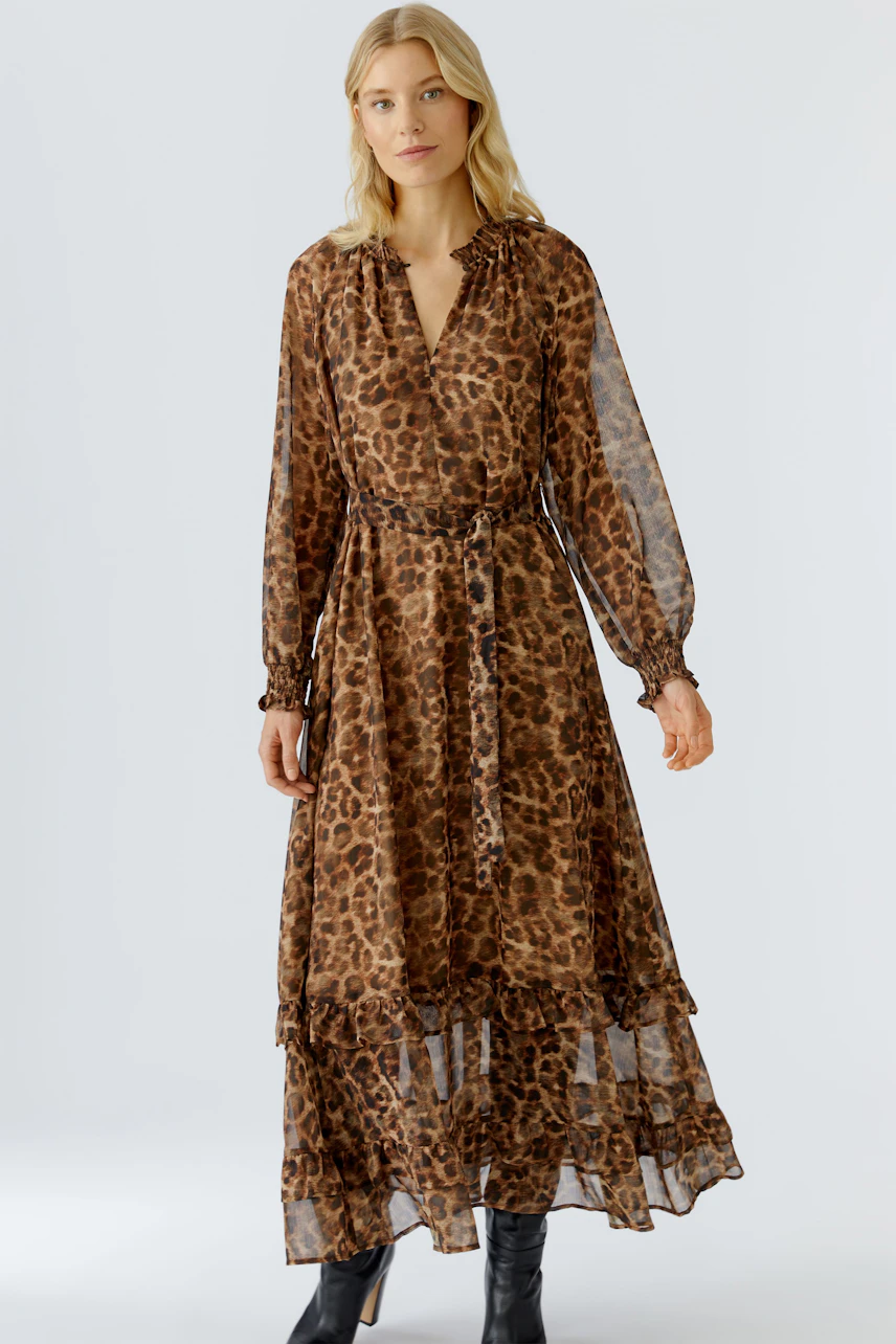 Maxikleid im Leo-Print: Frau trägt ein luftiges, langes Kleid mit Rüschendetails und Bindegürtel.